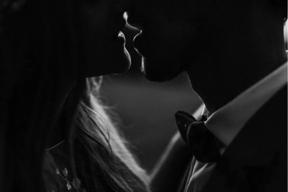 Silhouettes de deux personnes, un homme et une femme, proches, sur le point de s'embrasser, en noir et blanc.