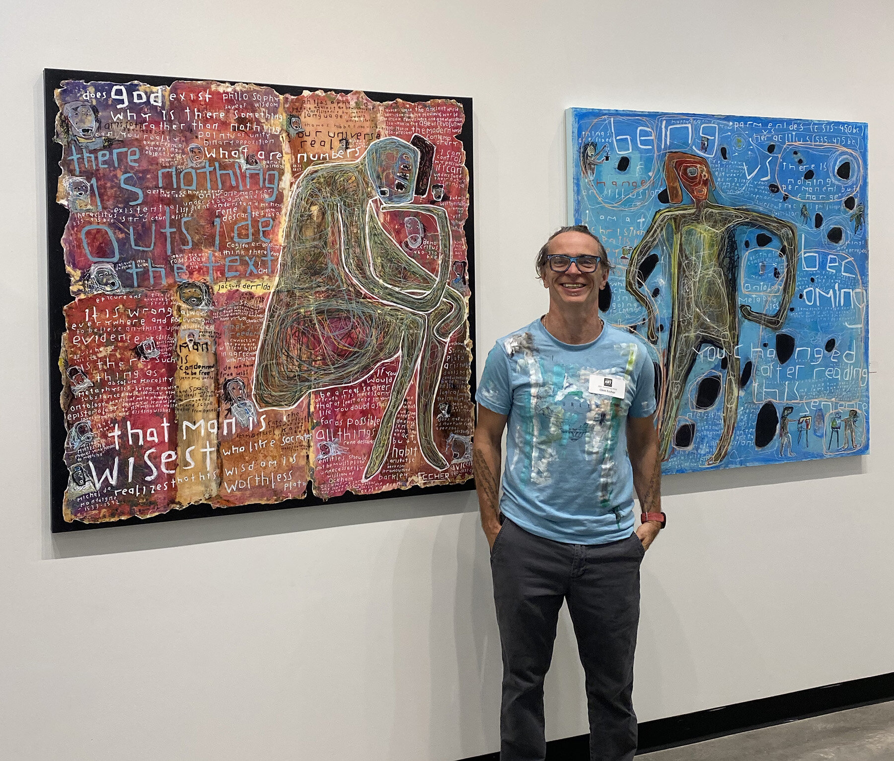   Clint Eccher  with his paintings “Glance at Philosophy” and “Being vs Becoming” 