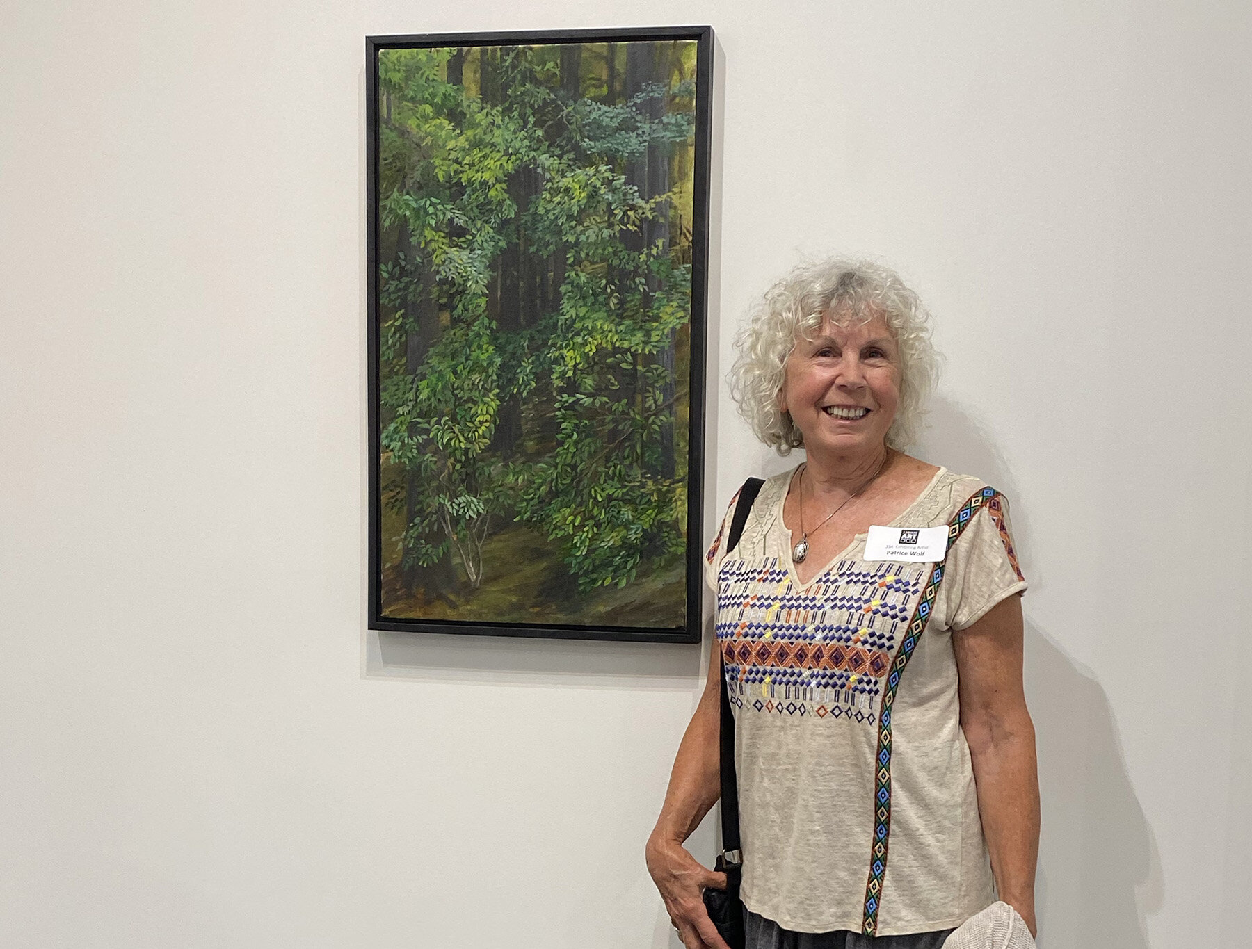   Patrice Wolf  with her painting “Self Portrait in Woods” 