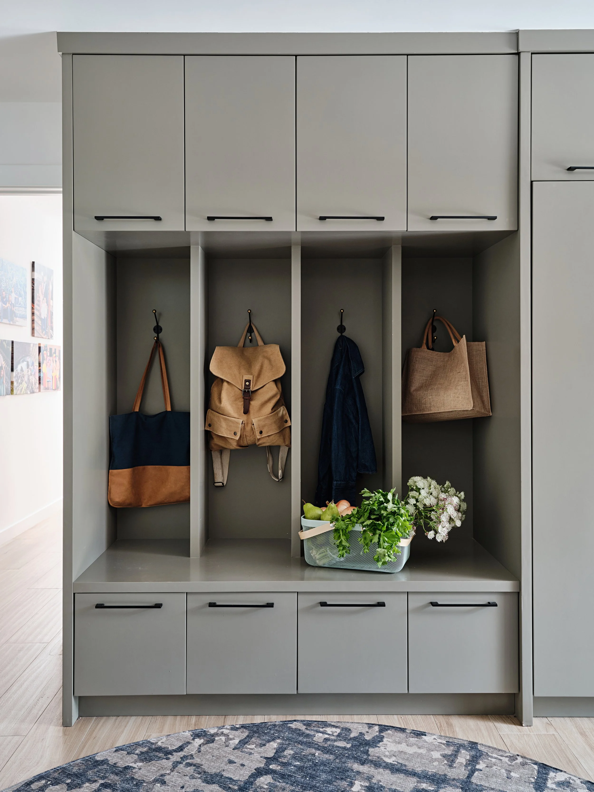 Khaki custom cabinetry in mudroom. Cubbies with hooks and storage. New construction home in South Florida. Interior design by Concept 2 Design.
