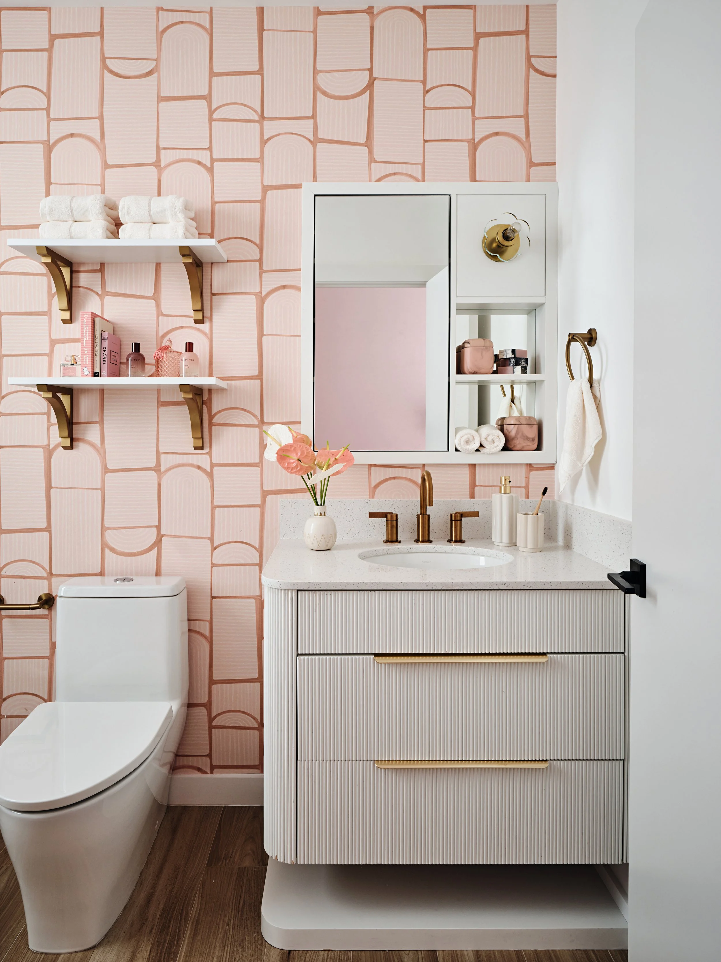 Pink wallpaper girls bathroom in residential home in South Florida. Fluted curved bathroom vanity. Interior design by Concept 2 Design.