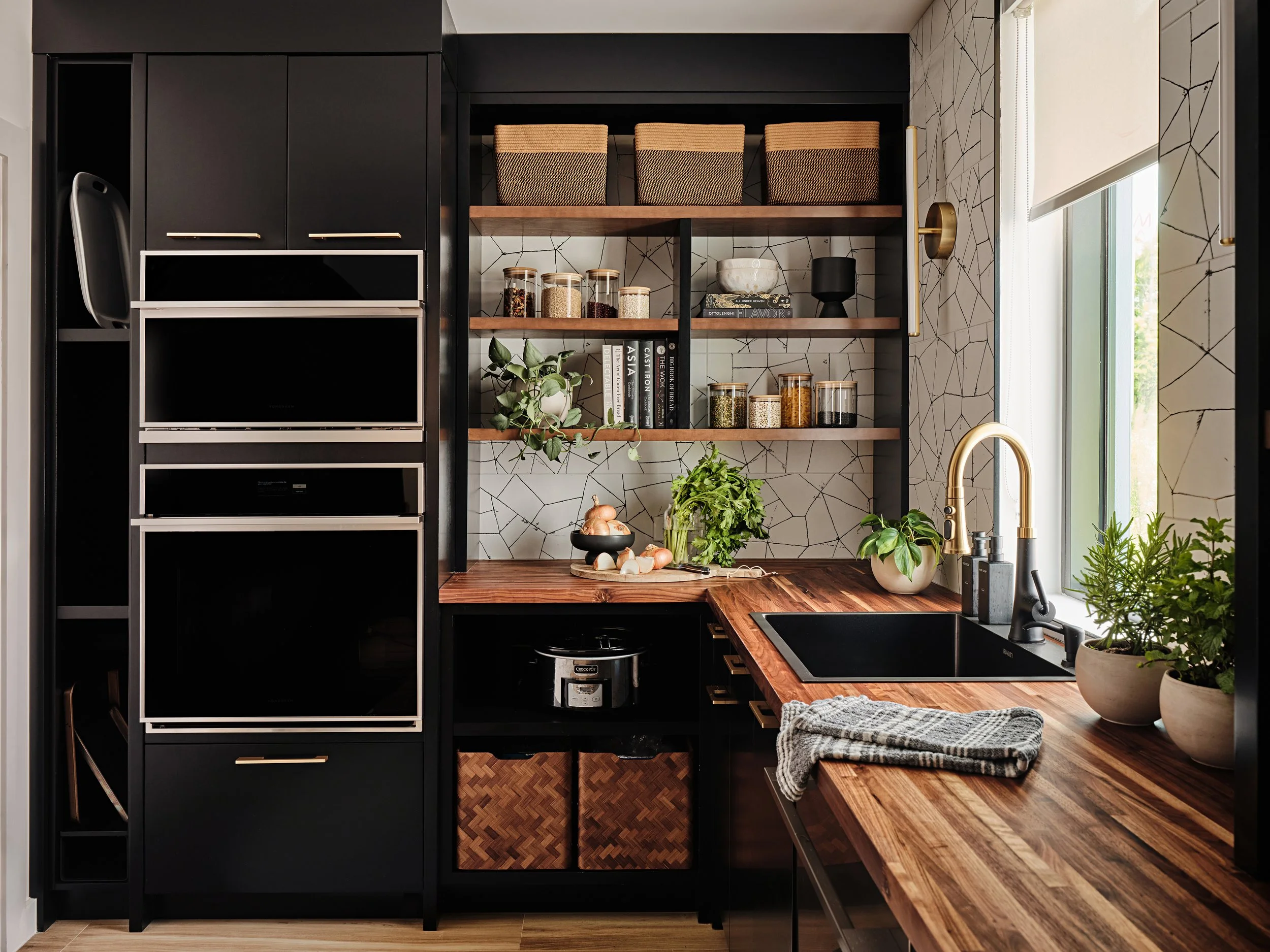 Black butlers pantry with double oven for a new construction home in Miami, FL. Interior design by Concept 2 Design.