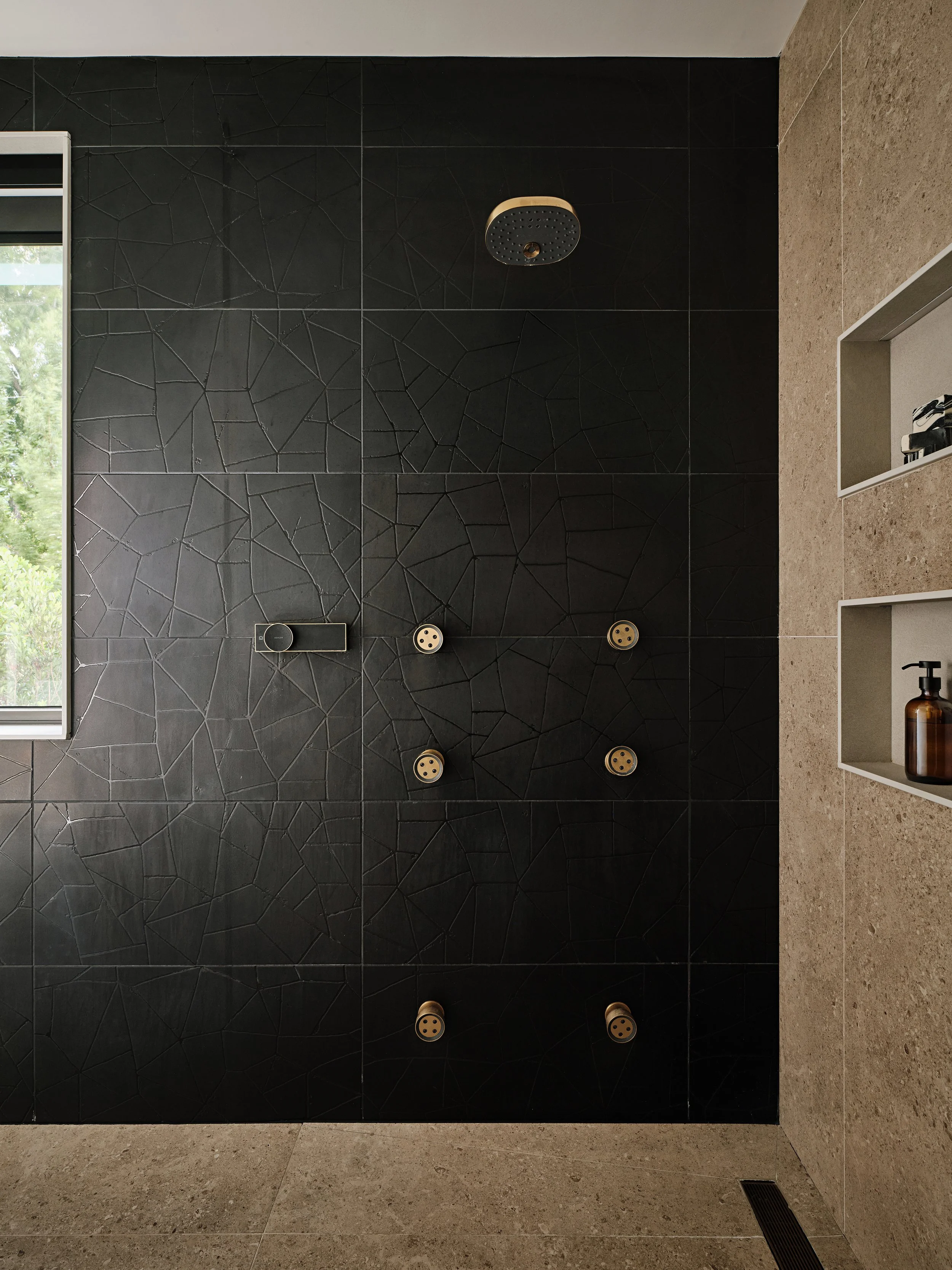 Black bathroom tile with brass fixtures.  Kohler statement bathroom fixtures. Smart bath features and linear drain. Interior Design by Concept 2 Design