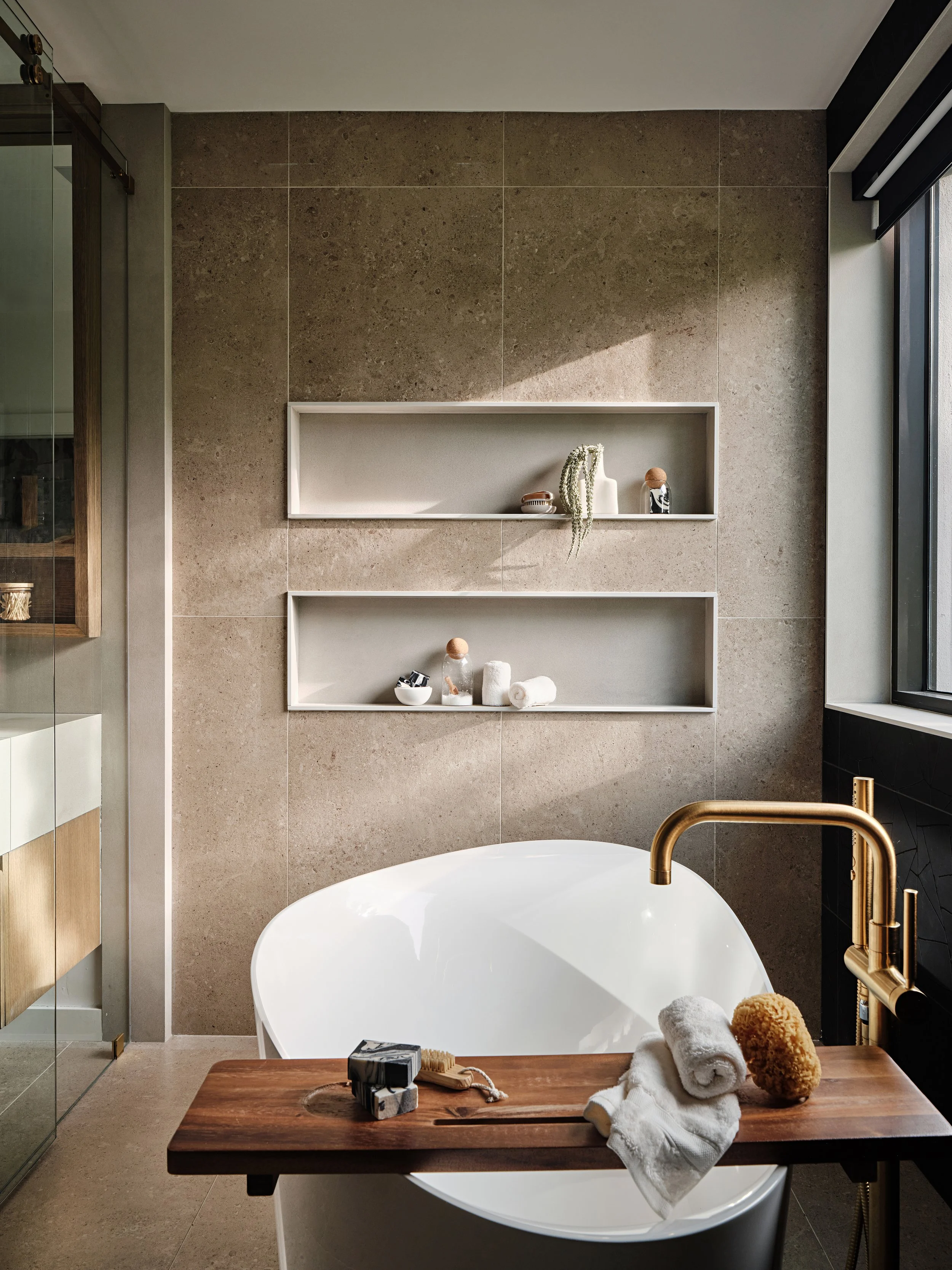 Veil bathtub in primary bathroom. Wet room with brass fixtures. Interior Design by Concept 2 Design