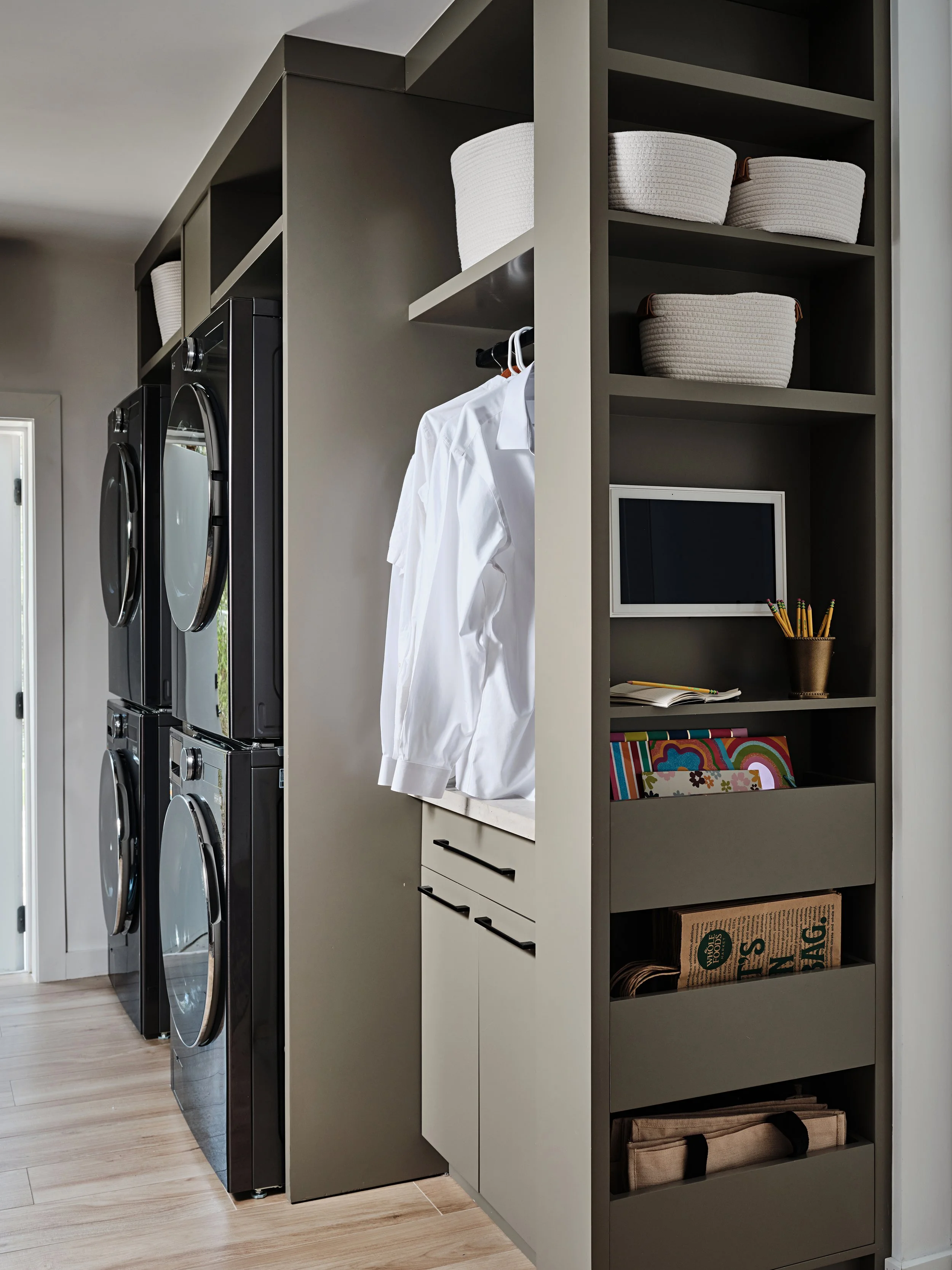 Khaki color custom cabinetry in  laundry room. Clothes hanging station in new construction home in South Florida. Interior design by Concept 2 Design.