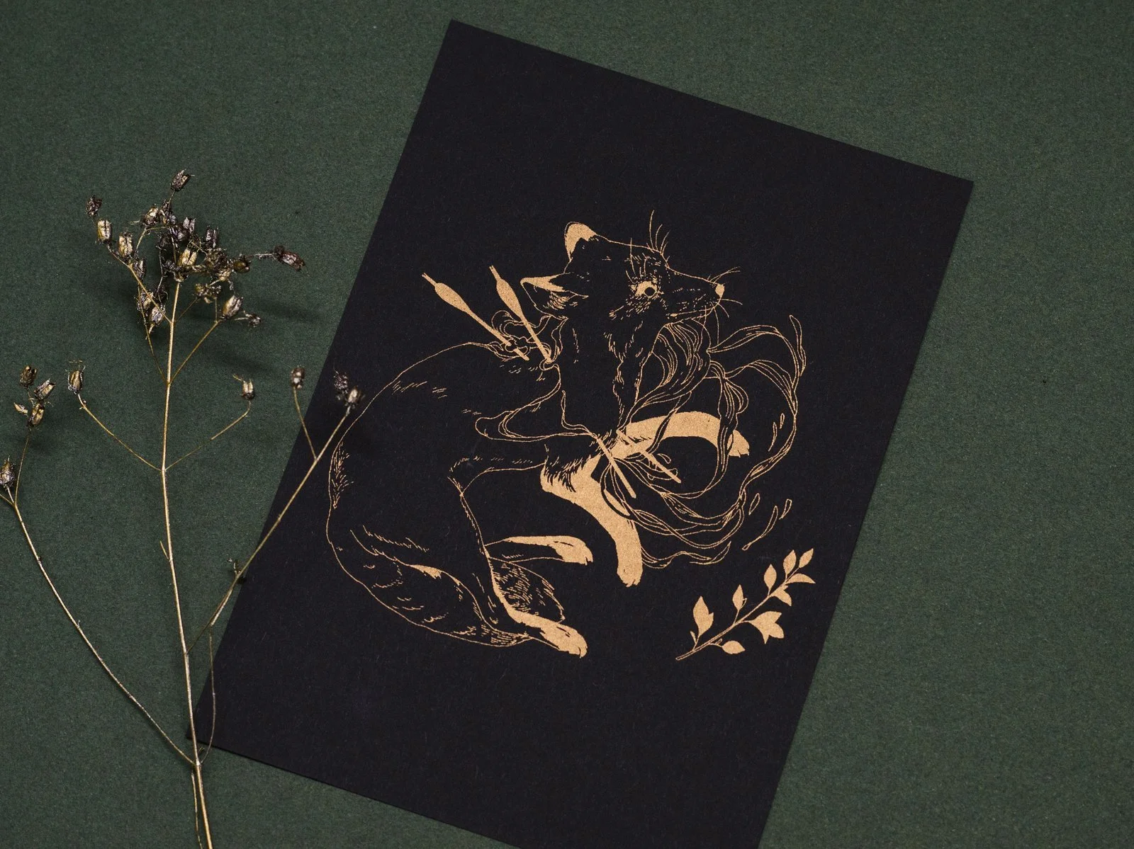Gold riso print of a wounded fox on black cardboard.