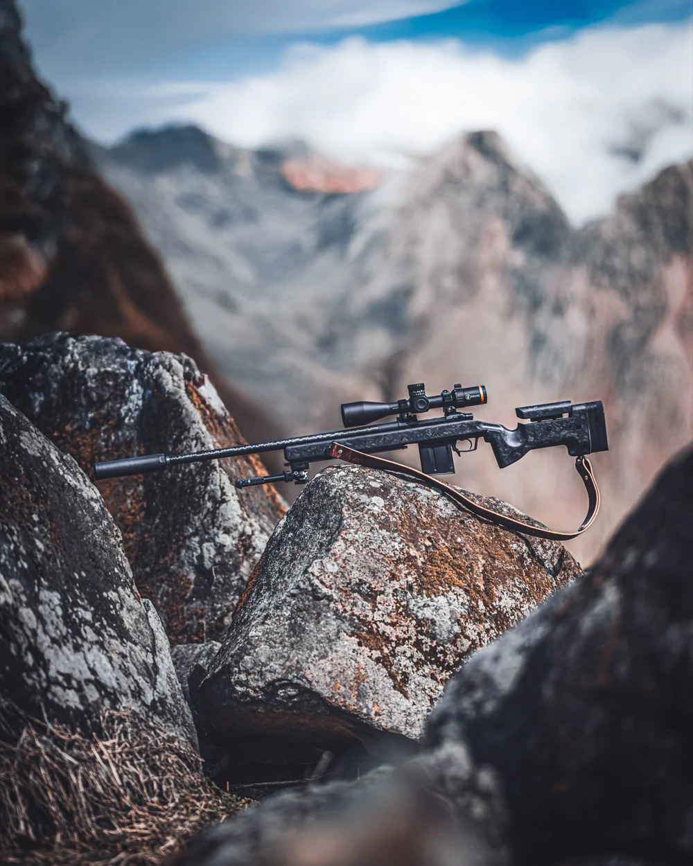 Precision rifle resting on rock with a mountain range beyond