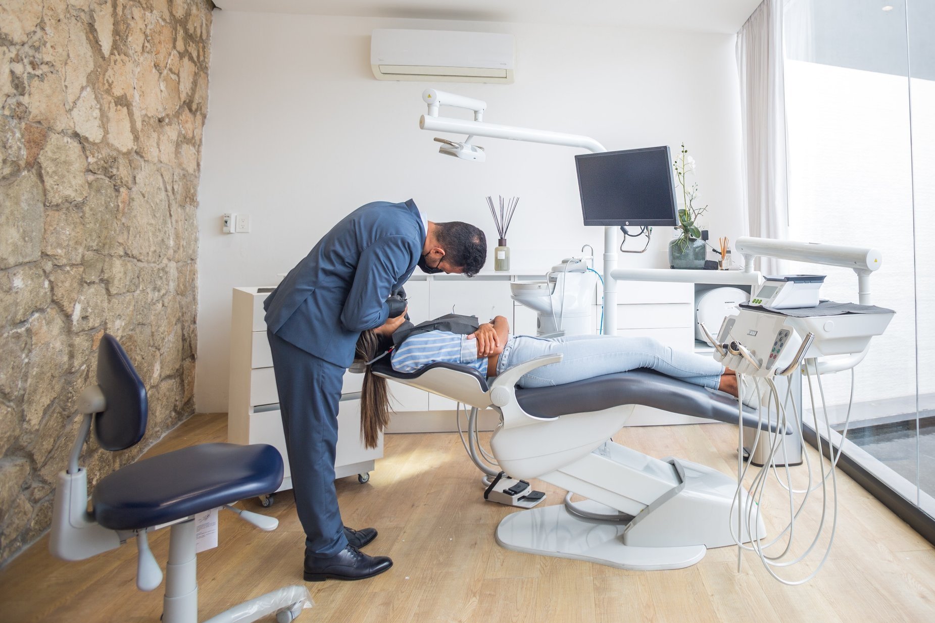 a dental hygienist hunches over a patient in the dentist chair