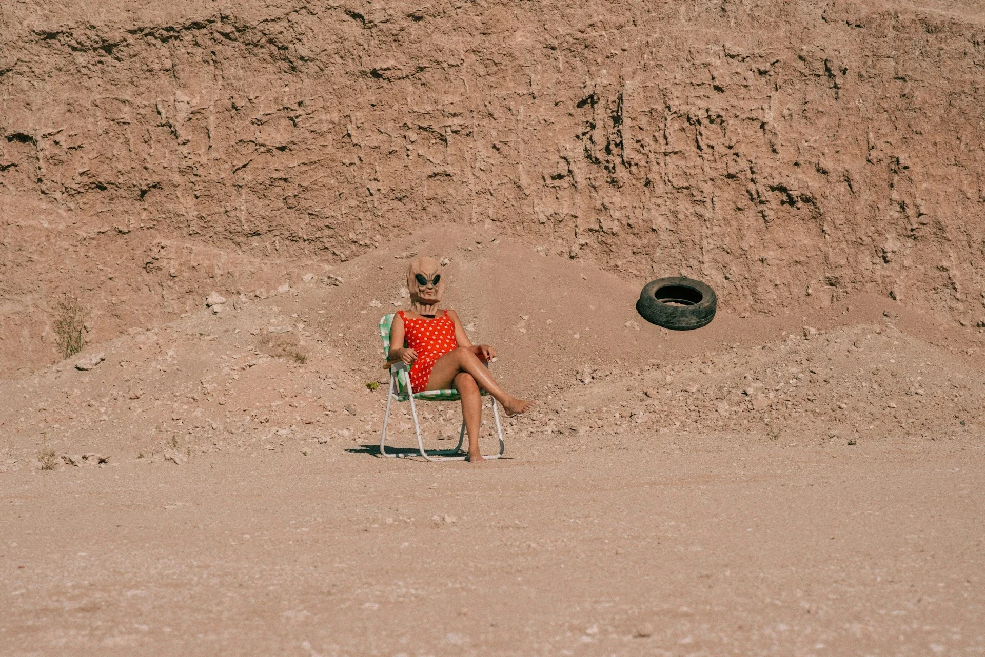 Surreal image of a person sitting in a chair on a barren, reddish landscape resembling the surface of Mars.
