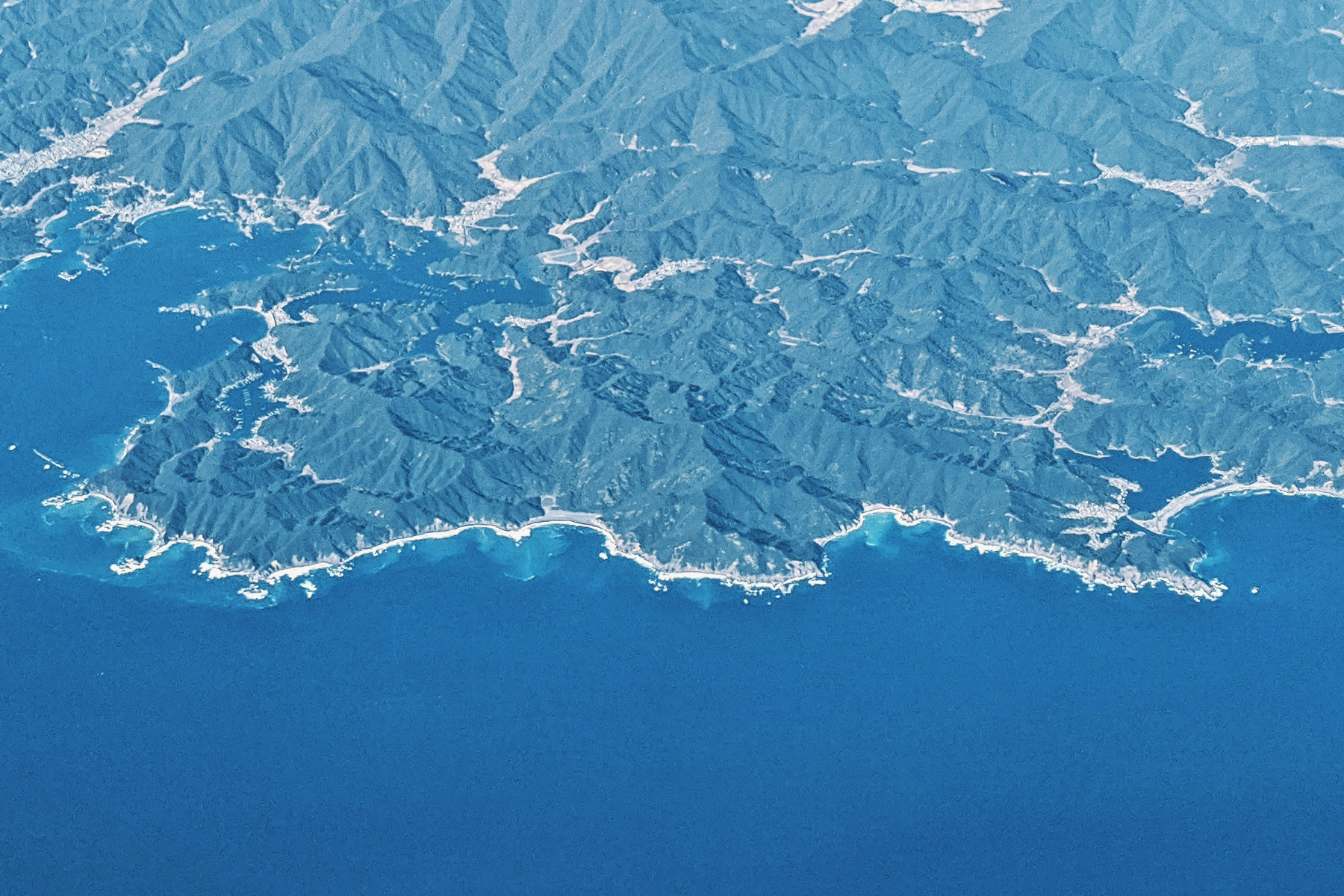 Aerial view of mountains and coastline illustrating how science, knowledge, and perspective shape meaning in Maria Popova's Traversal