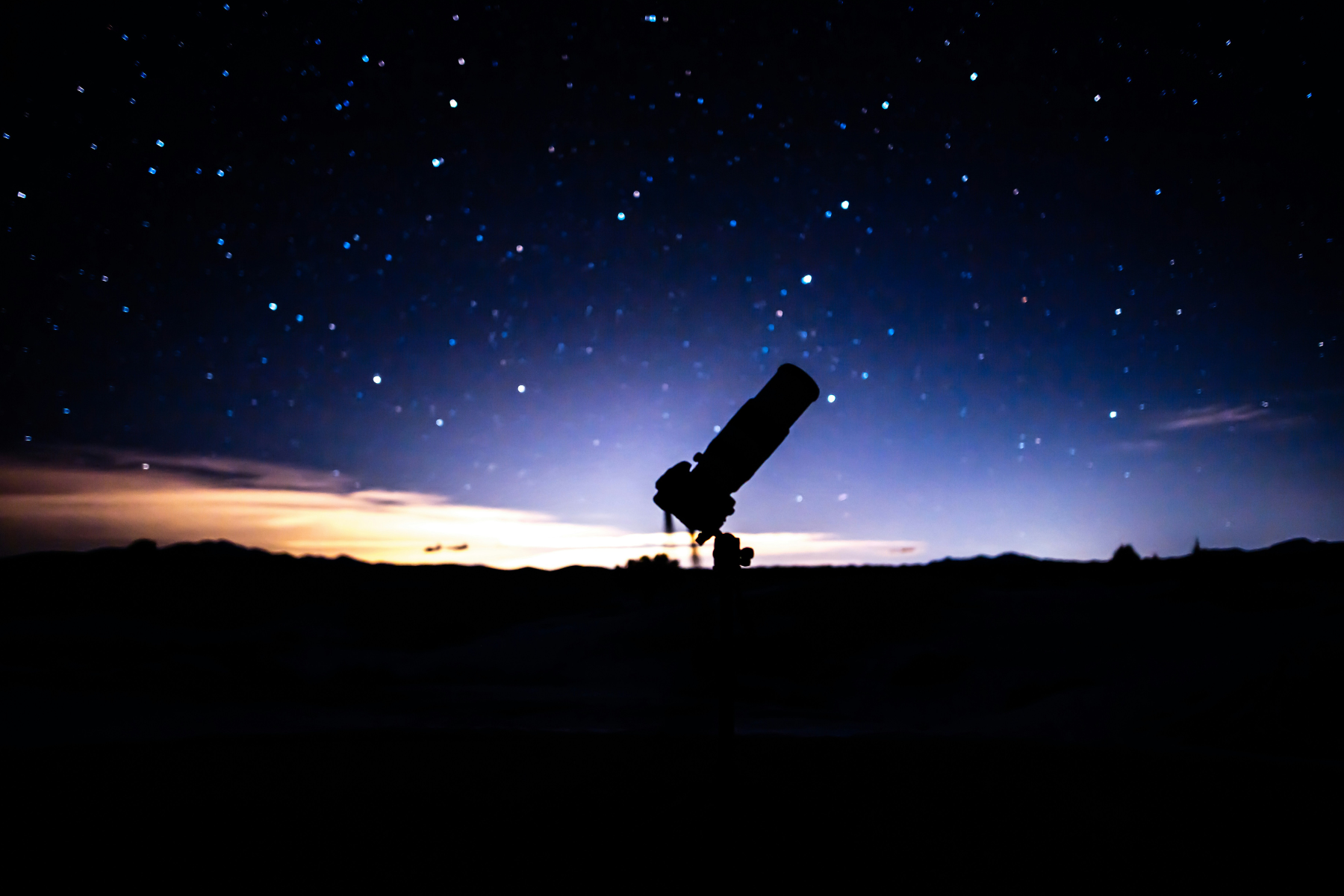 Telescope under a star-filled sky representing curiosity, exploration, and the search for meaning in Maria Popova's book Traversal, reviewed by Dr. Tiffany Vora.