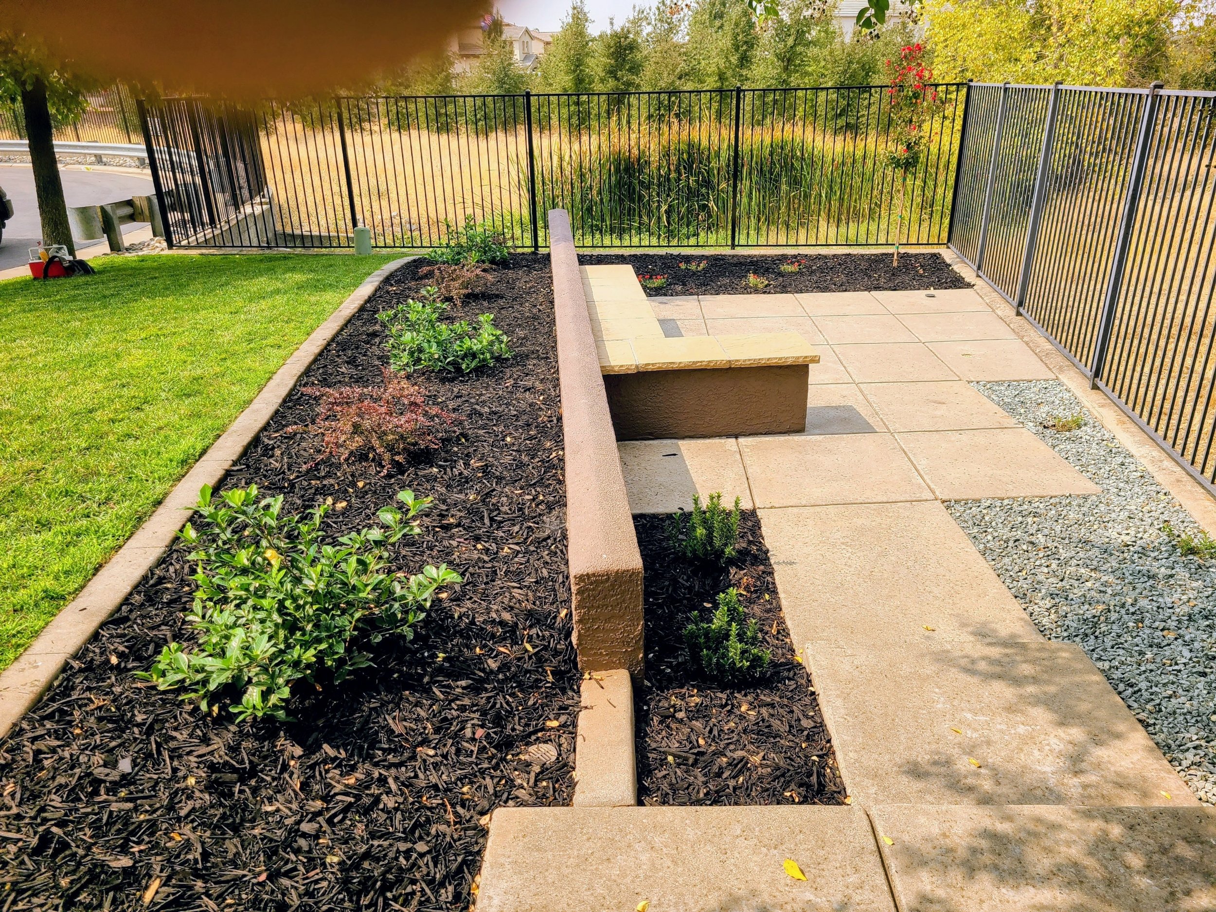 Backyard patio with raised planter beds, fresh mulch, concrete pavers, and custom landscape design.