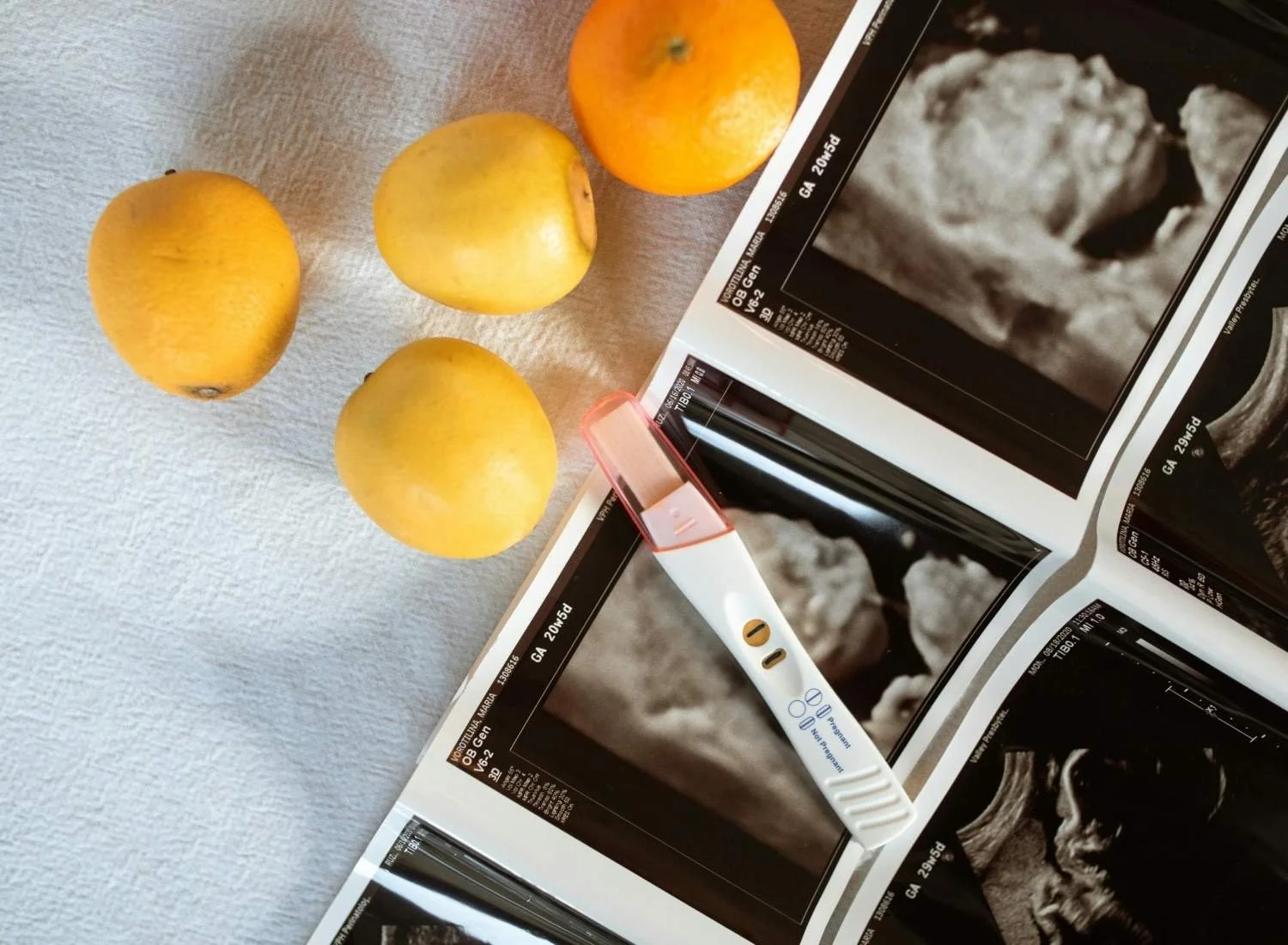 Image of early pregnancy test, ultrasound and fruit.