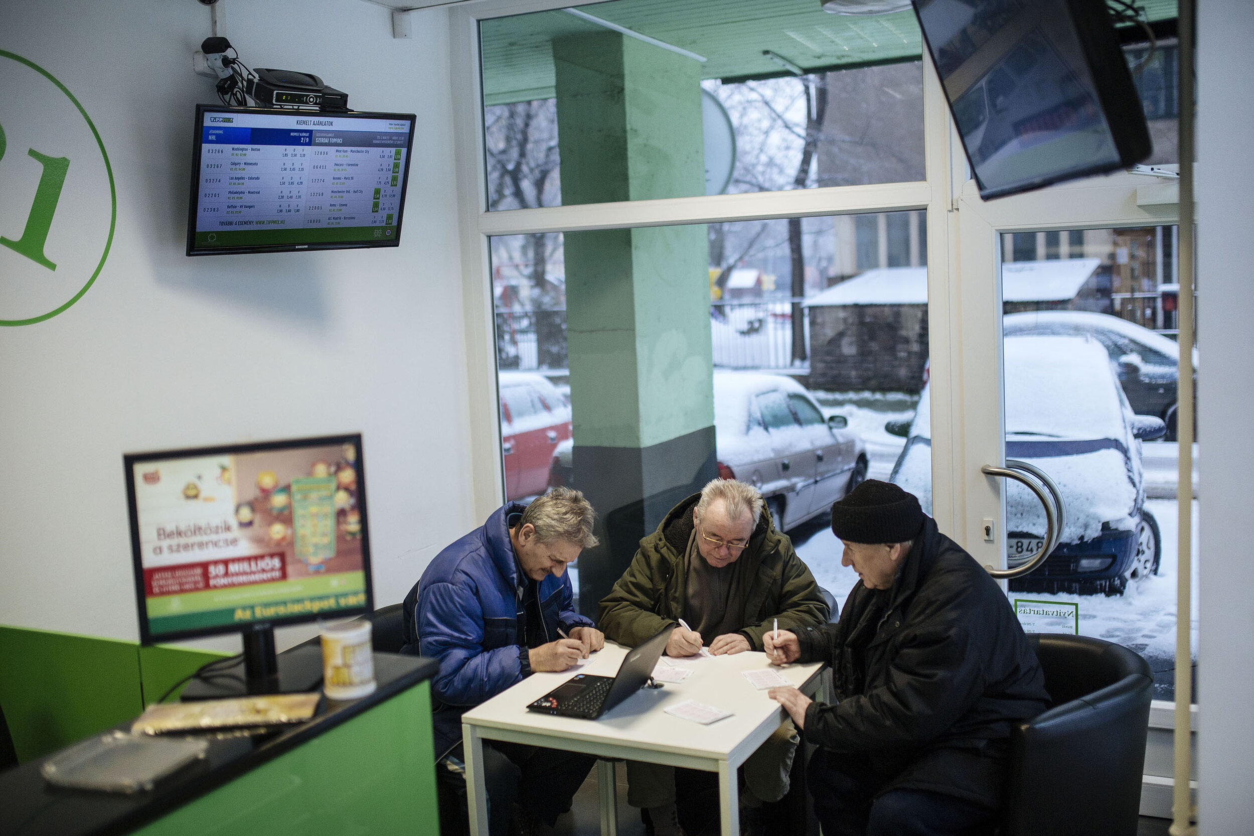  Nándi (right) and his friends are at the lottery ticket shop at half past seven. Every morning they manage to find a quarter of an hour to discuss political issues besides the events of the previous day and pulling each other’s leg. Only after this 