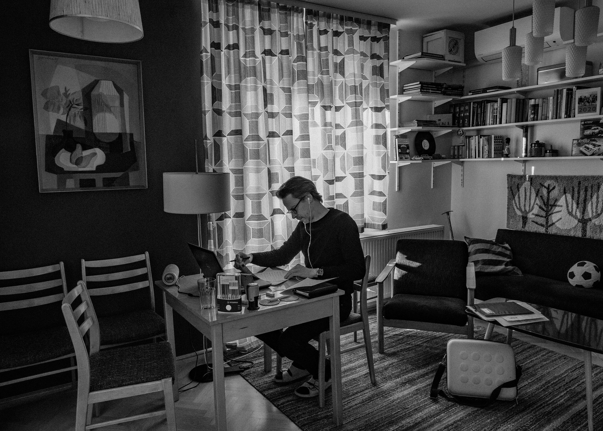   Péter  verifying his notes behind his desk in his living room in Budapest. He and his family have worked from home since the beginning of the pandemic. His daughter, who is finishing high-school this year, from home as well, often uses his “officia