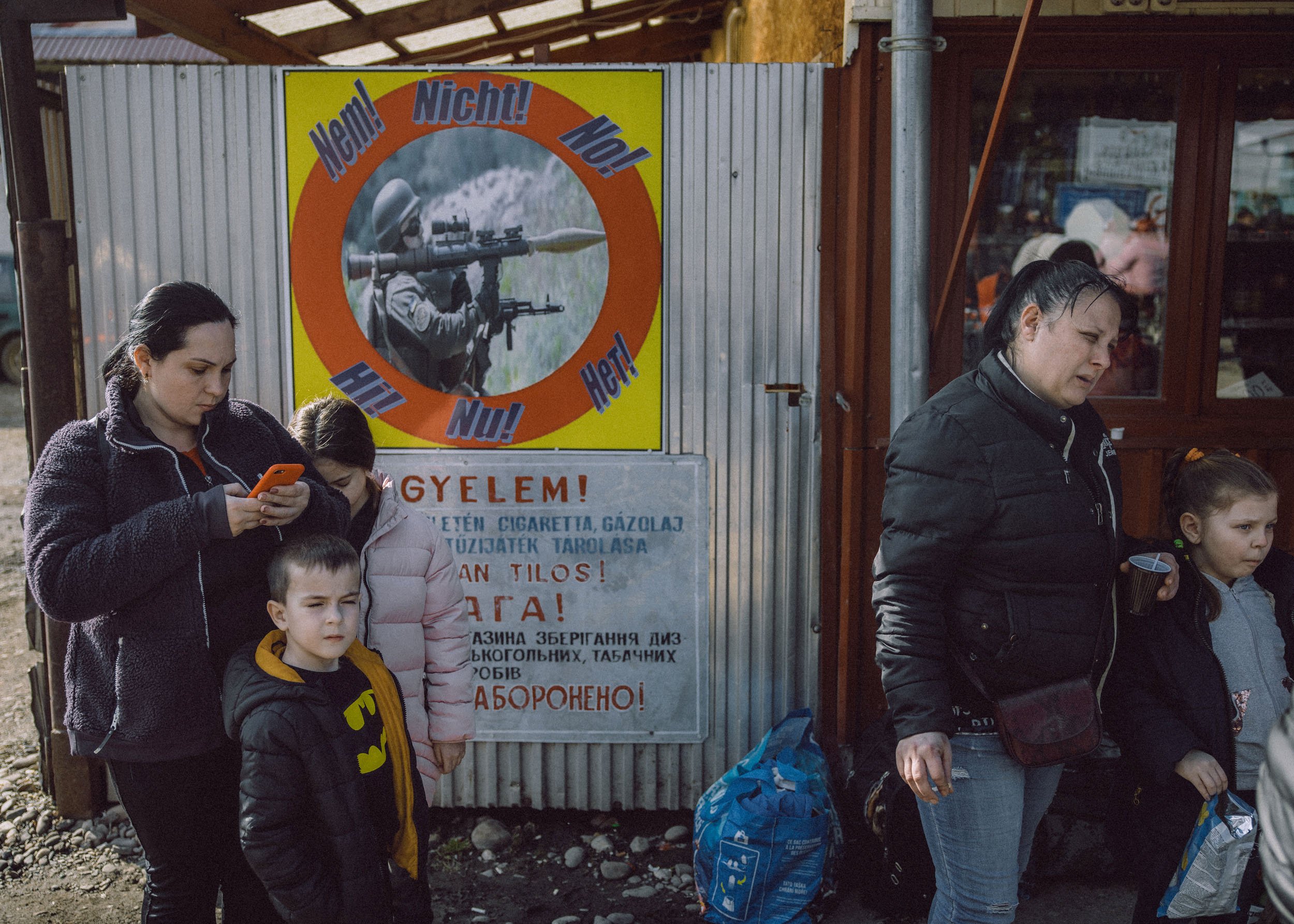  People wait with their belongings at the Tiszabecs-Tiszaujlak border crossing as they flee Ukraine on February 25, 2022 in Tiszabecs, Hungary 