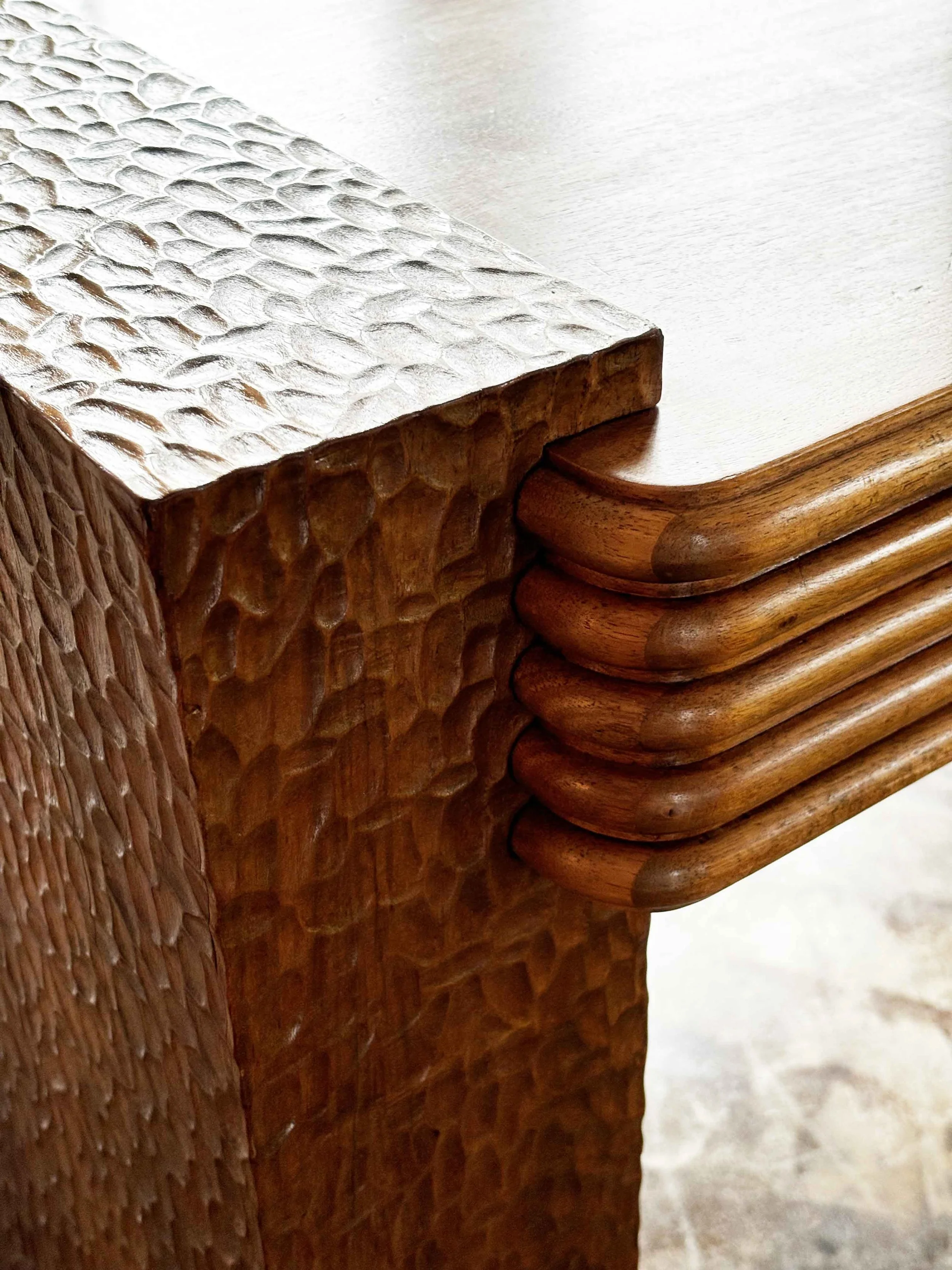 Close-up of a wooden table corner with a textured metallic decorative box on top.