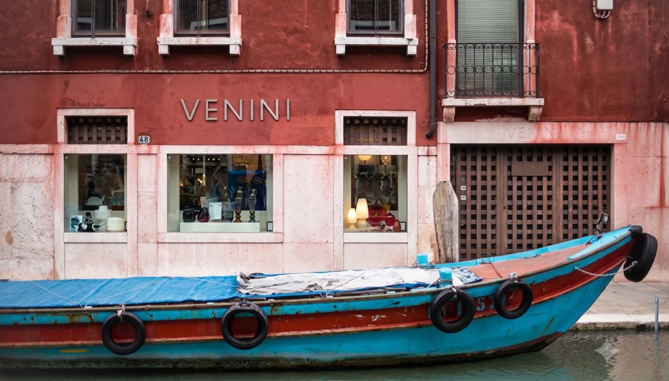 A boat docked in front of a building with the sign 'VENINI' on it.