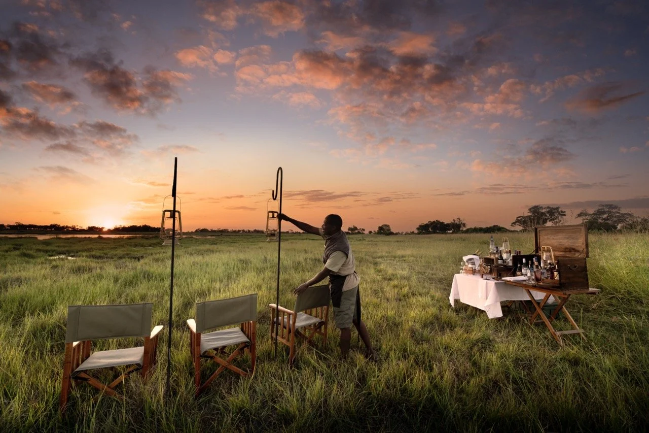 Exclusive African safari sundowner with drinks setup in the bush at sunset, showcasing a personalized luxury travel experience.