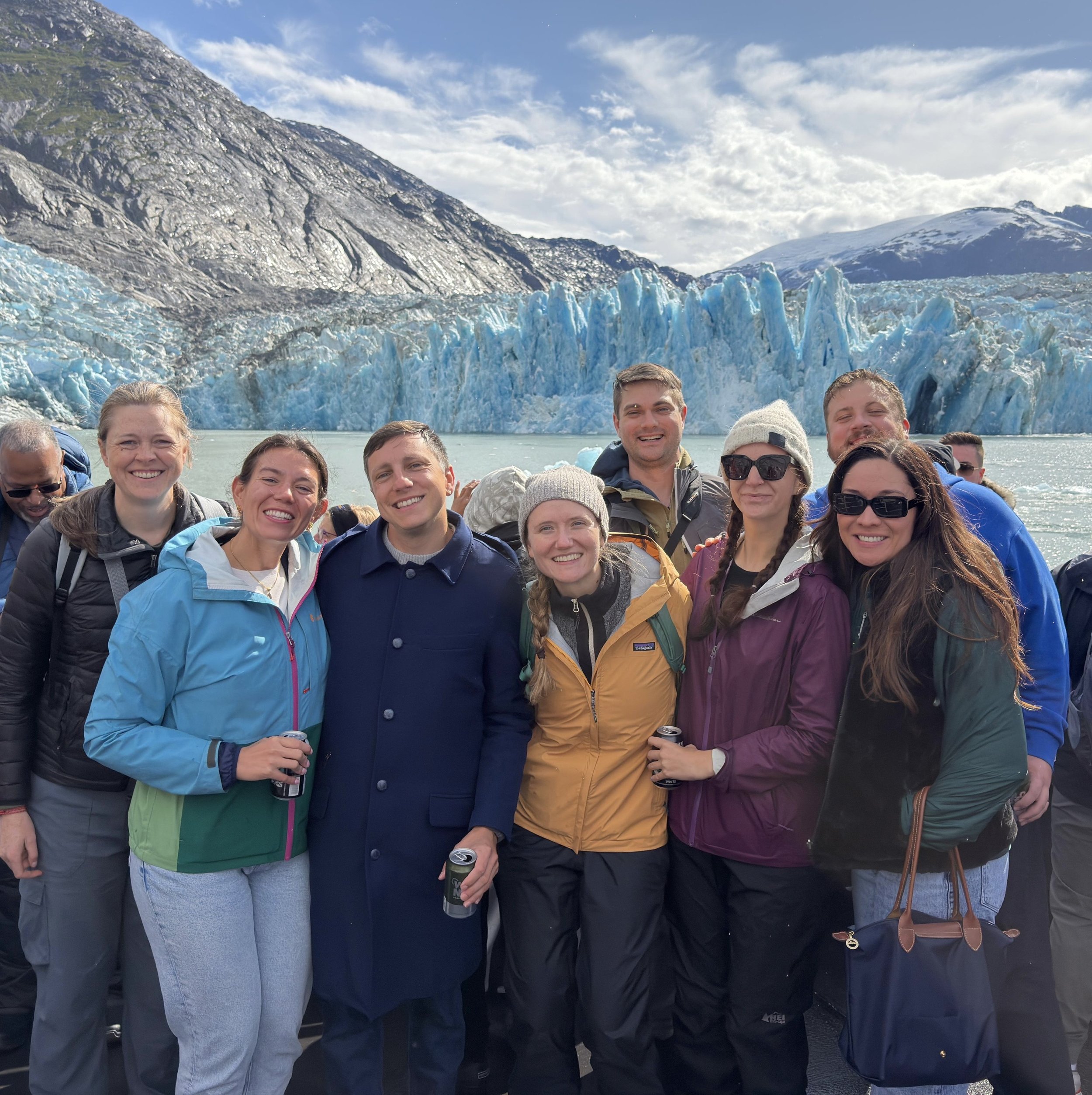 The group of friends on a boat in front of the glacier.