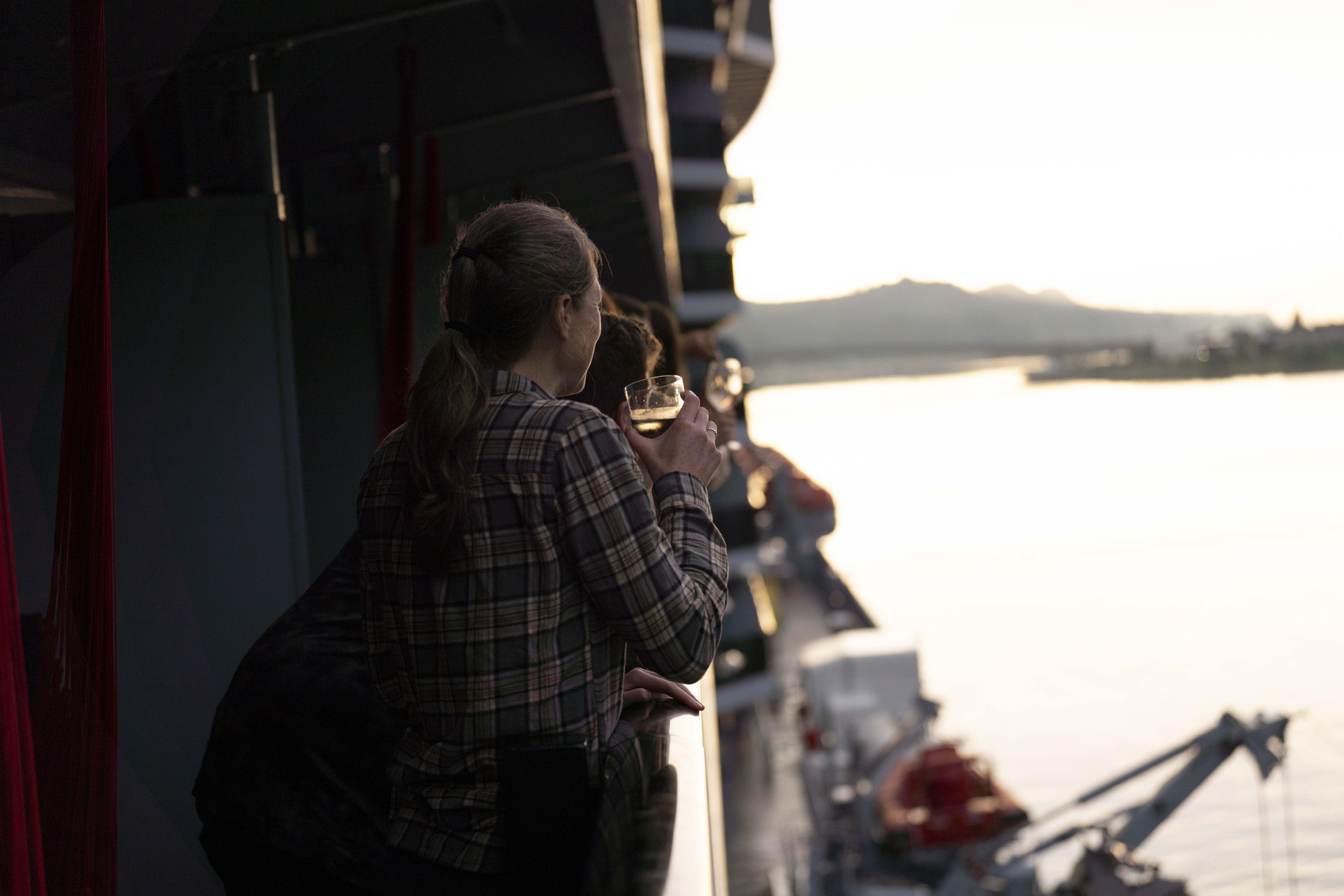 People standing on a cruise ship deck and drinking wine in the sunset light.