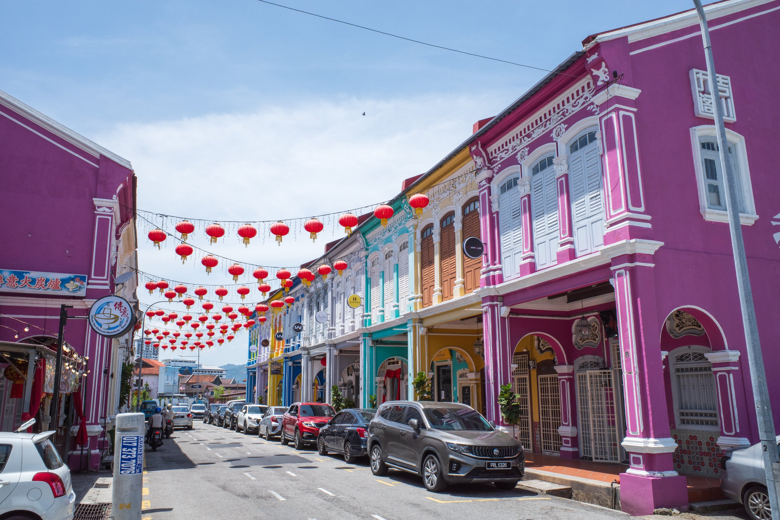 Lanterns hanging between colorful colonial buildings.