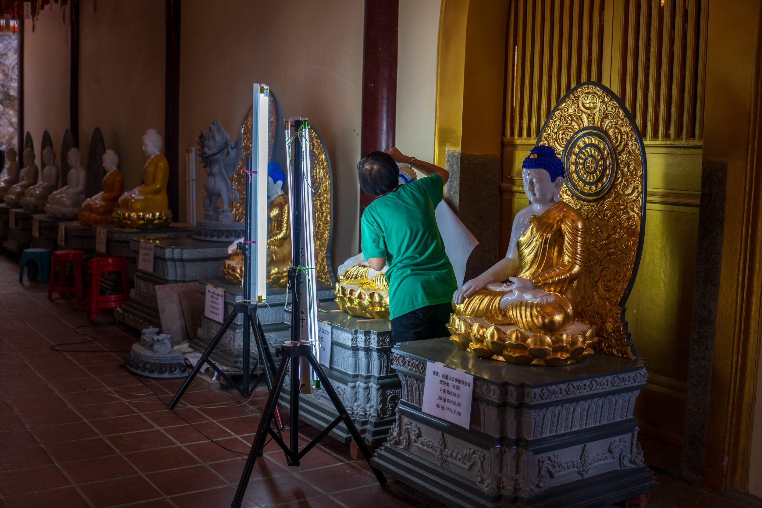 A person painting blue hair on a statue.
