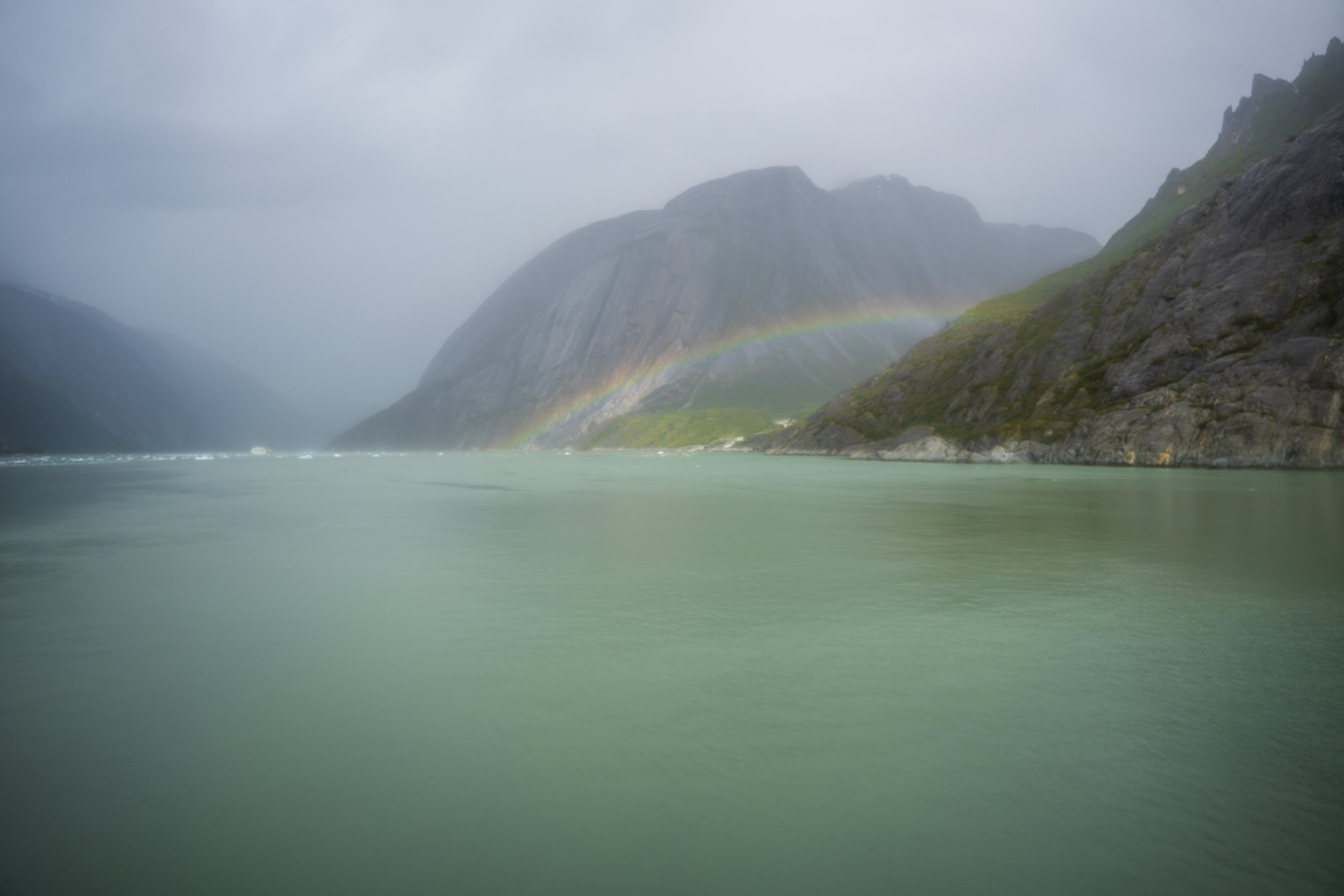 A rainbow between misty fjords.