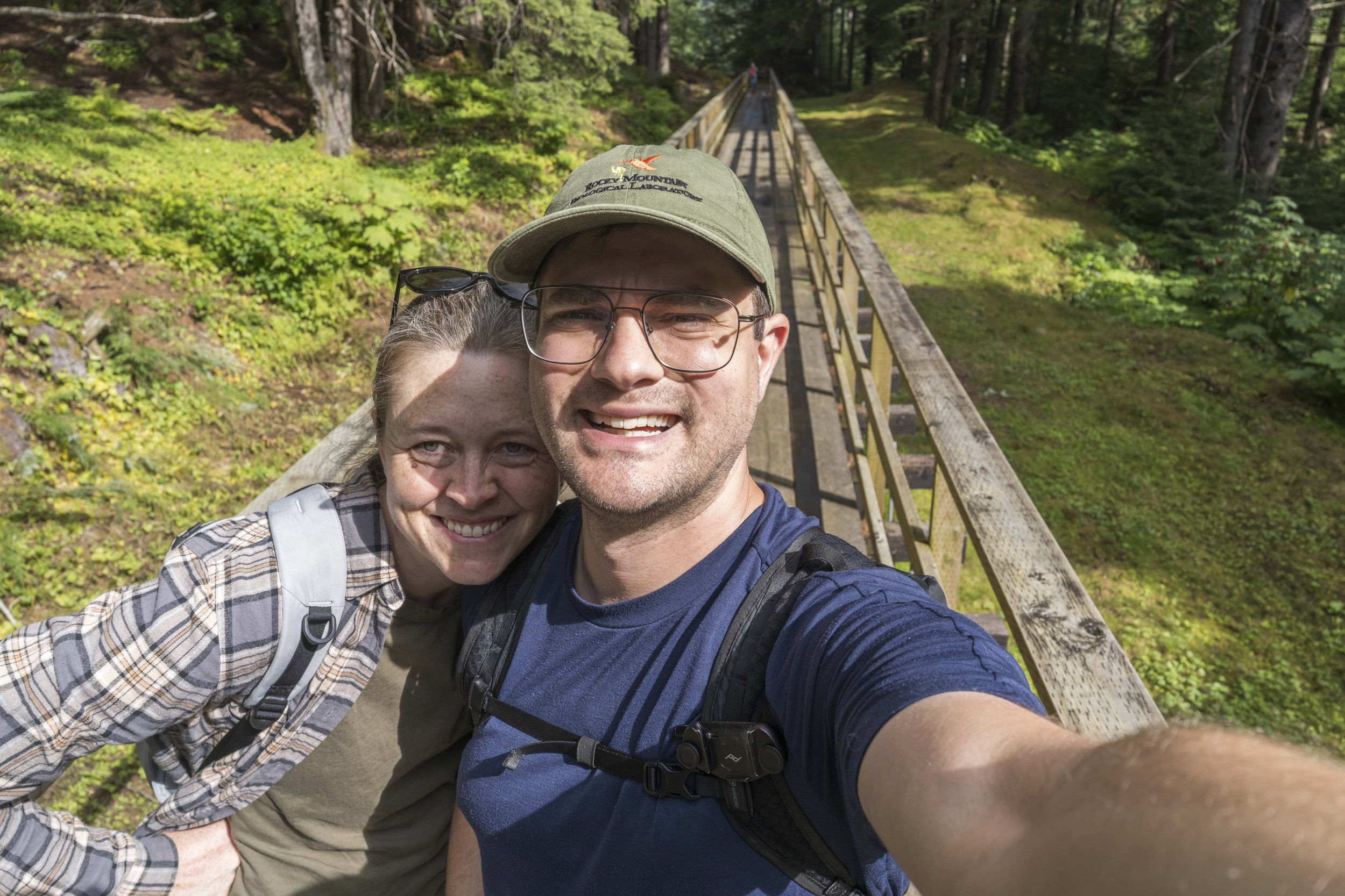 A selfie of Nicole and Jason on a wood walkway in a forest.