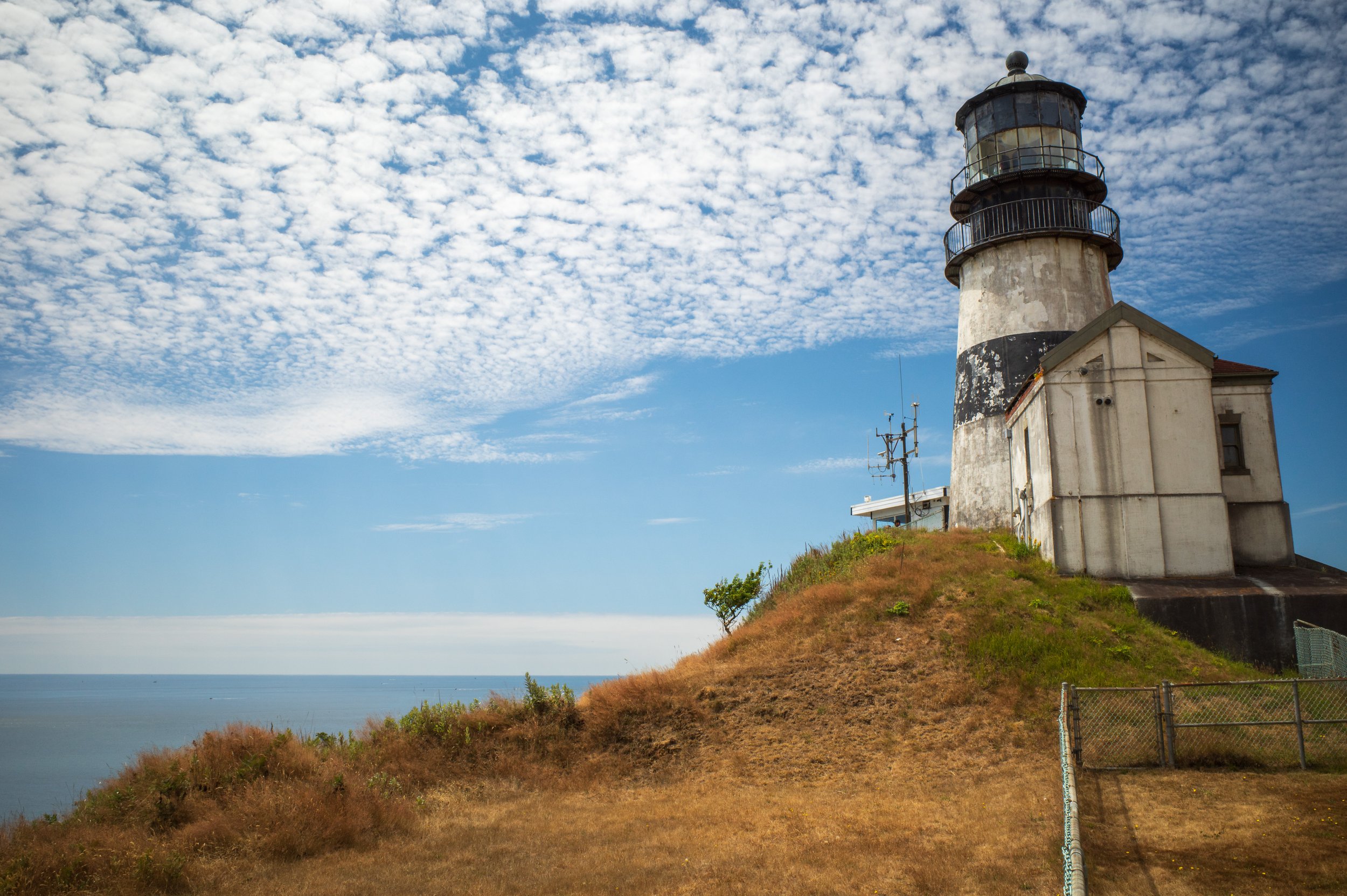 A small black and white lighthouse on a cliff.