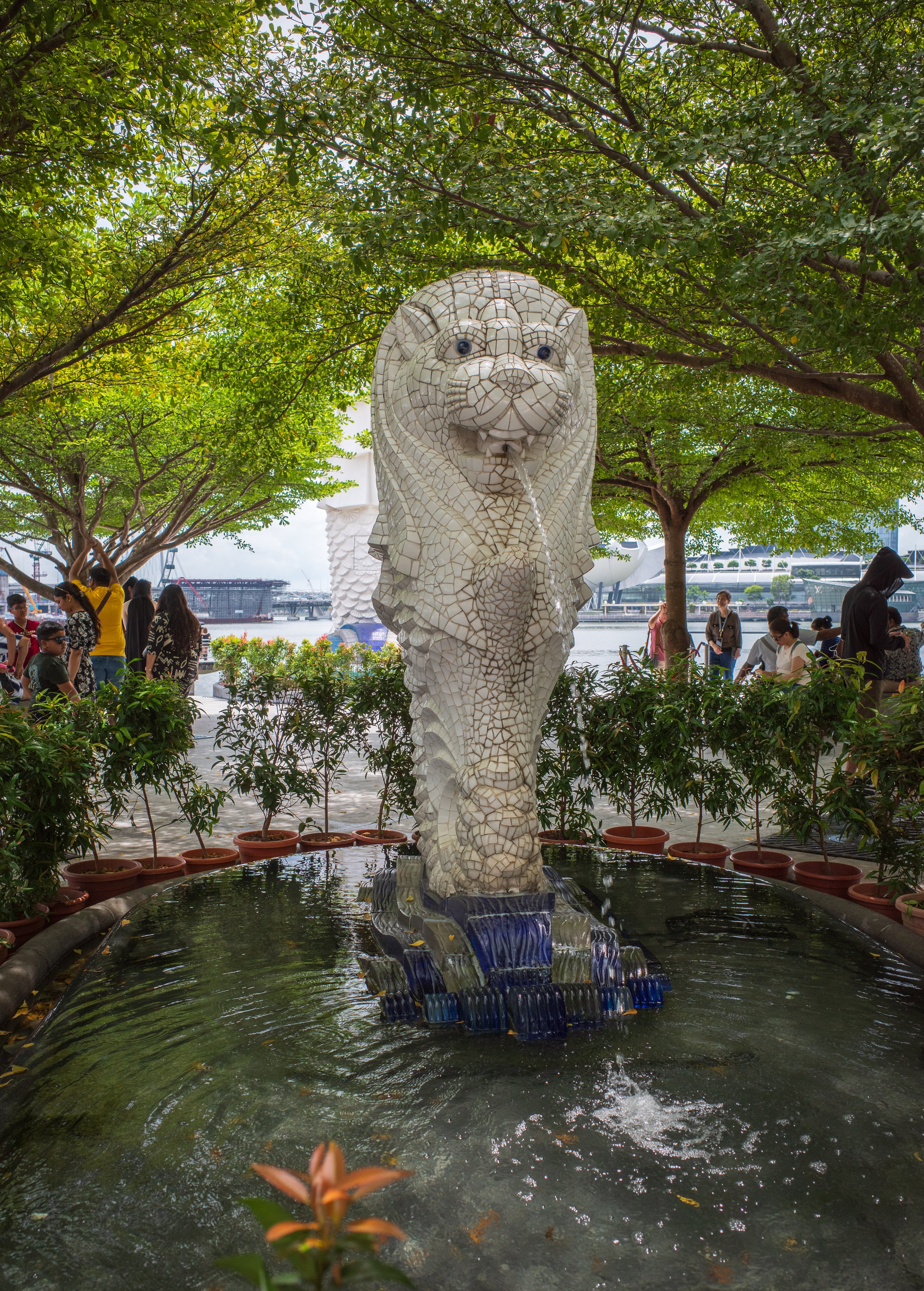A smaller, tiled merlion fountain among small trees.