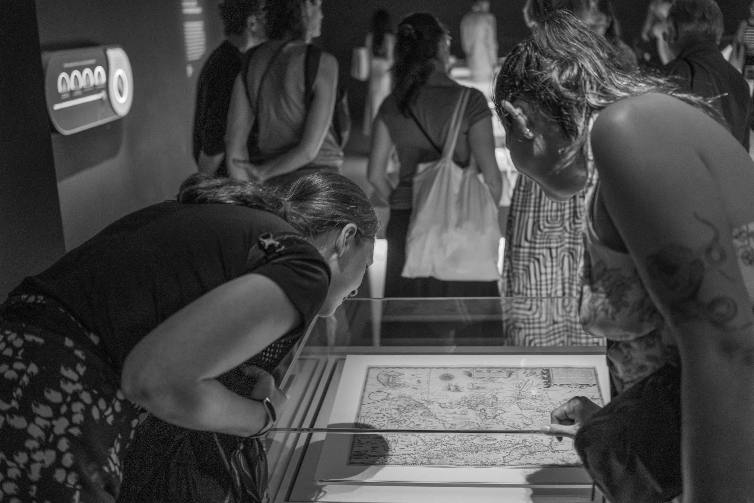 Nicole and Bella leaning down to examine a glass-covered map.