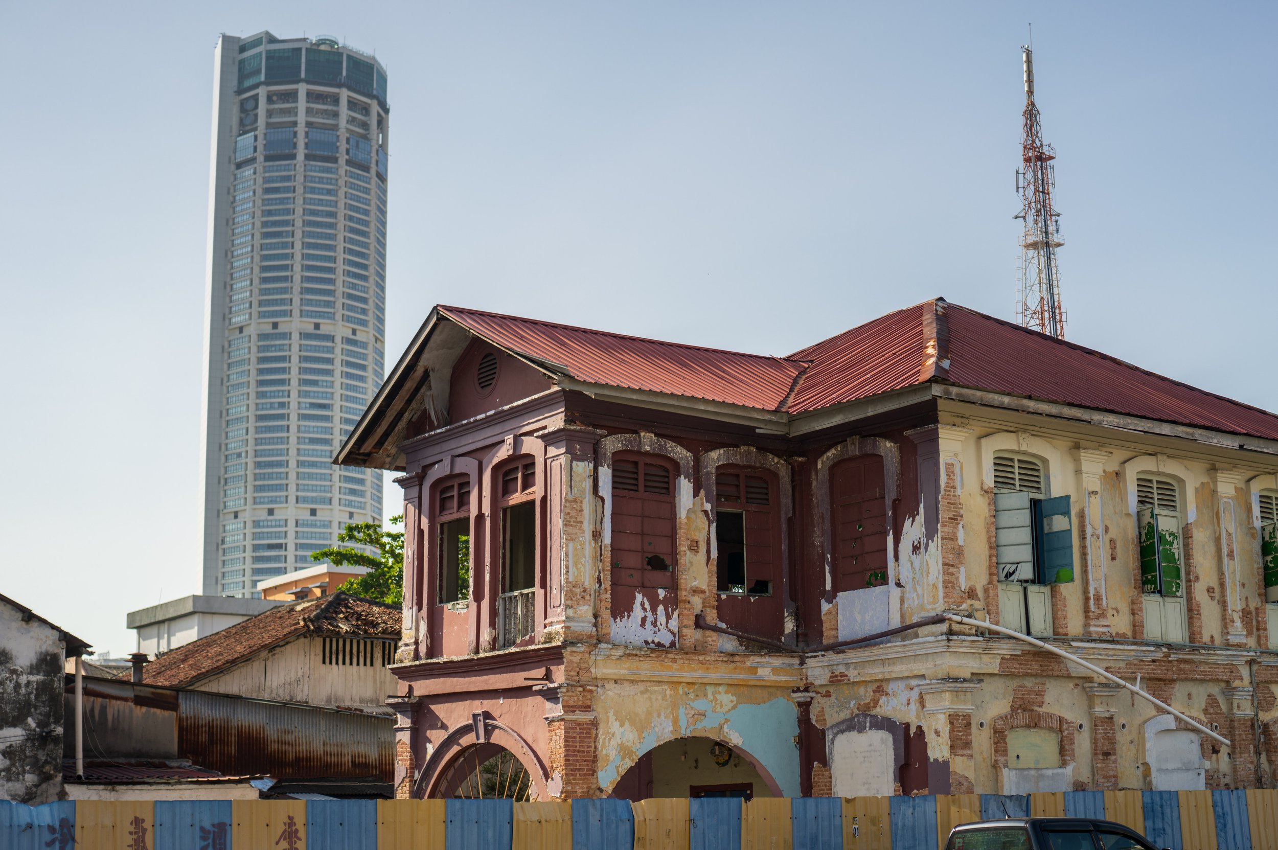 A old building with peeling paint in front of a modern skyscraper.