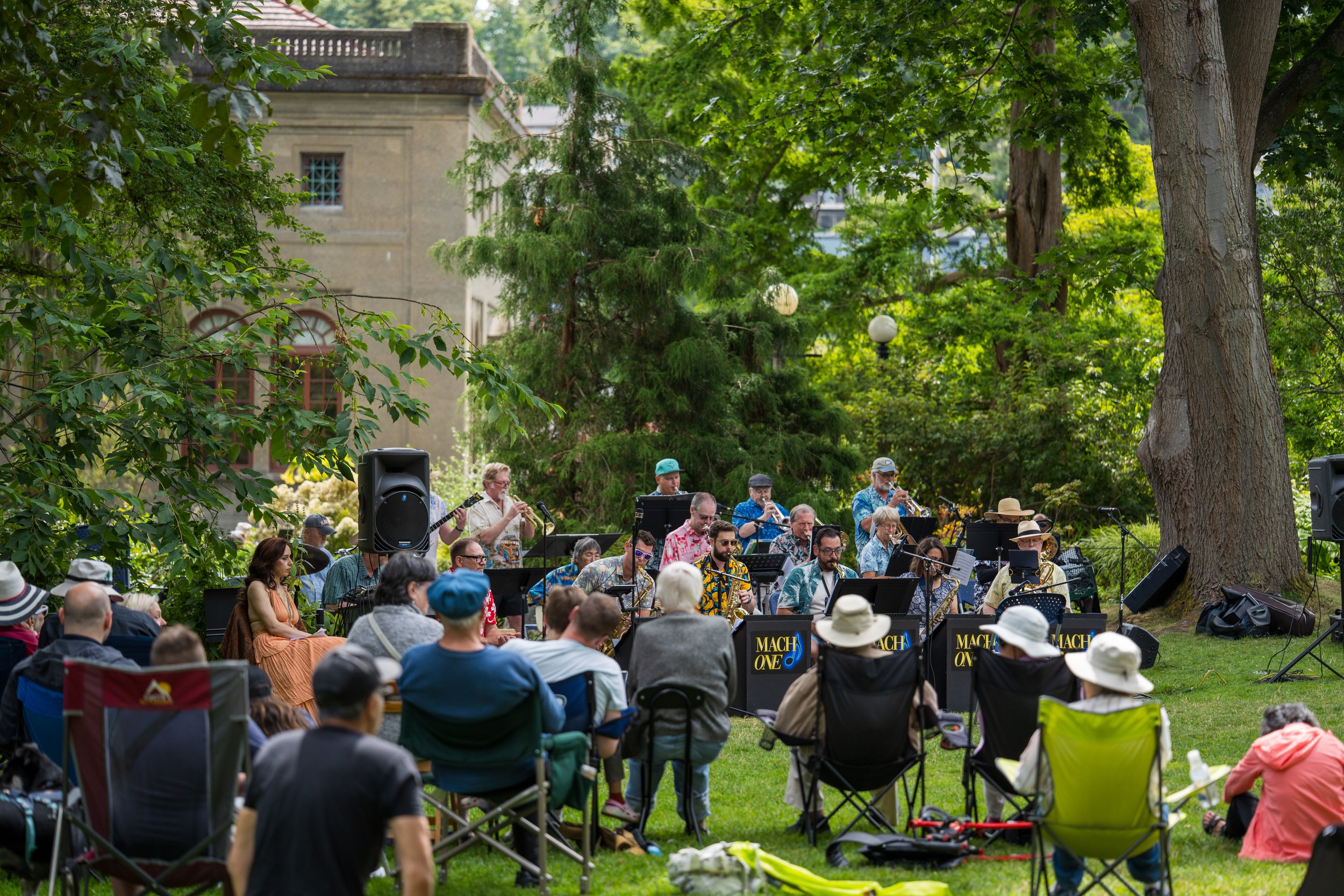 A crowd watching a band play on a grassy clearing.
