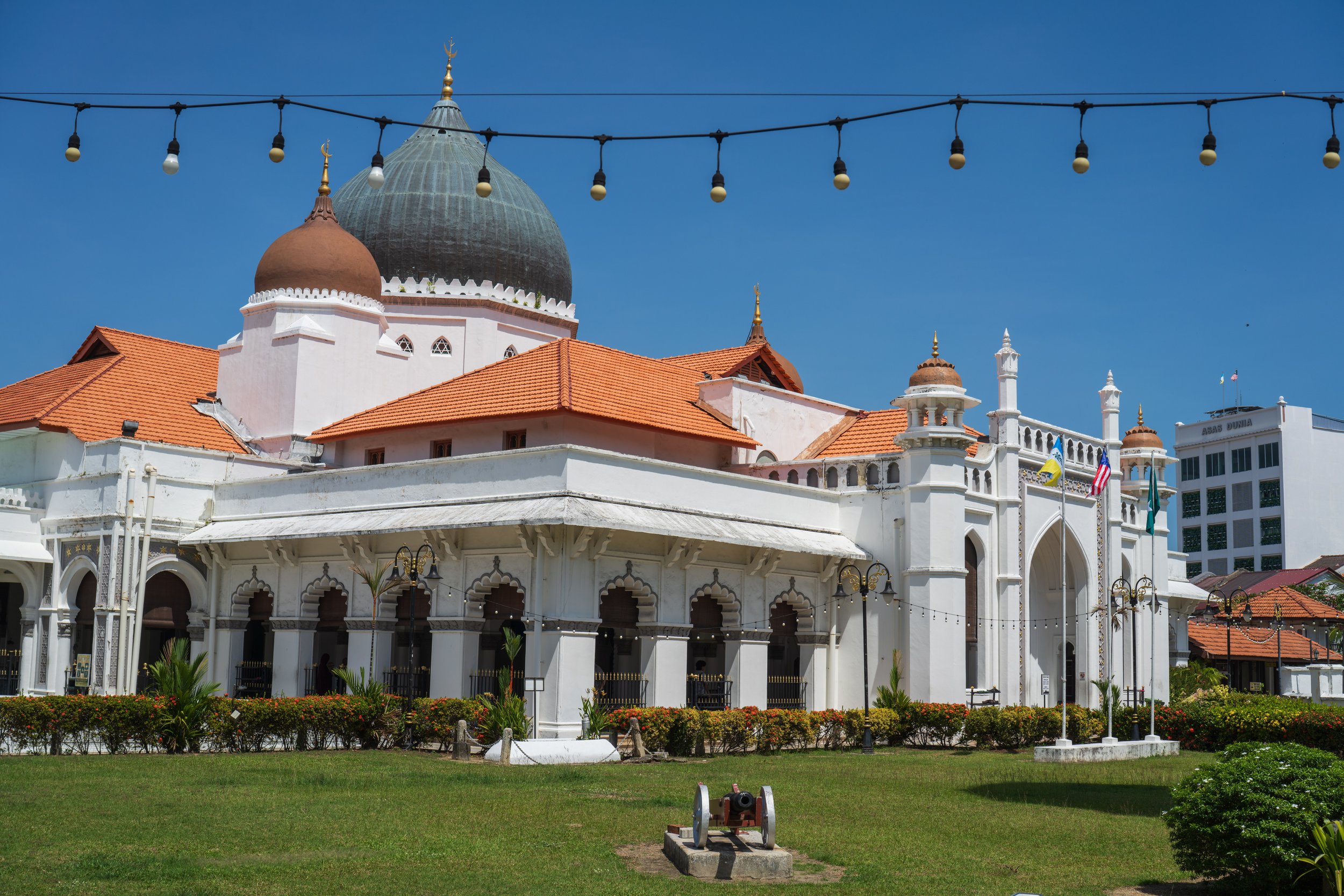 A large mosque against a green lawn and blue sky.