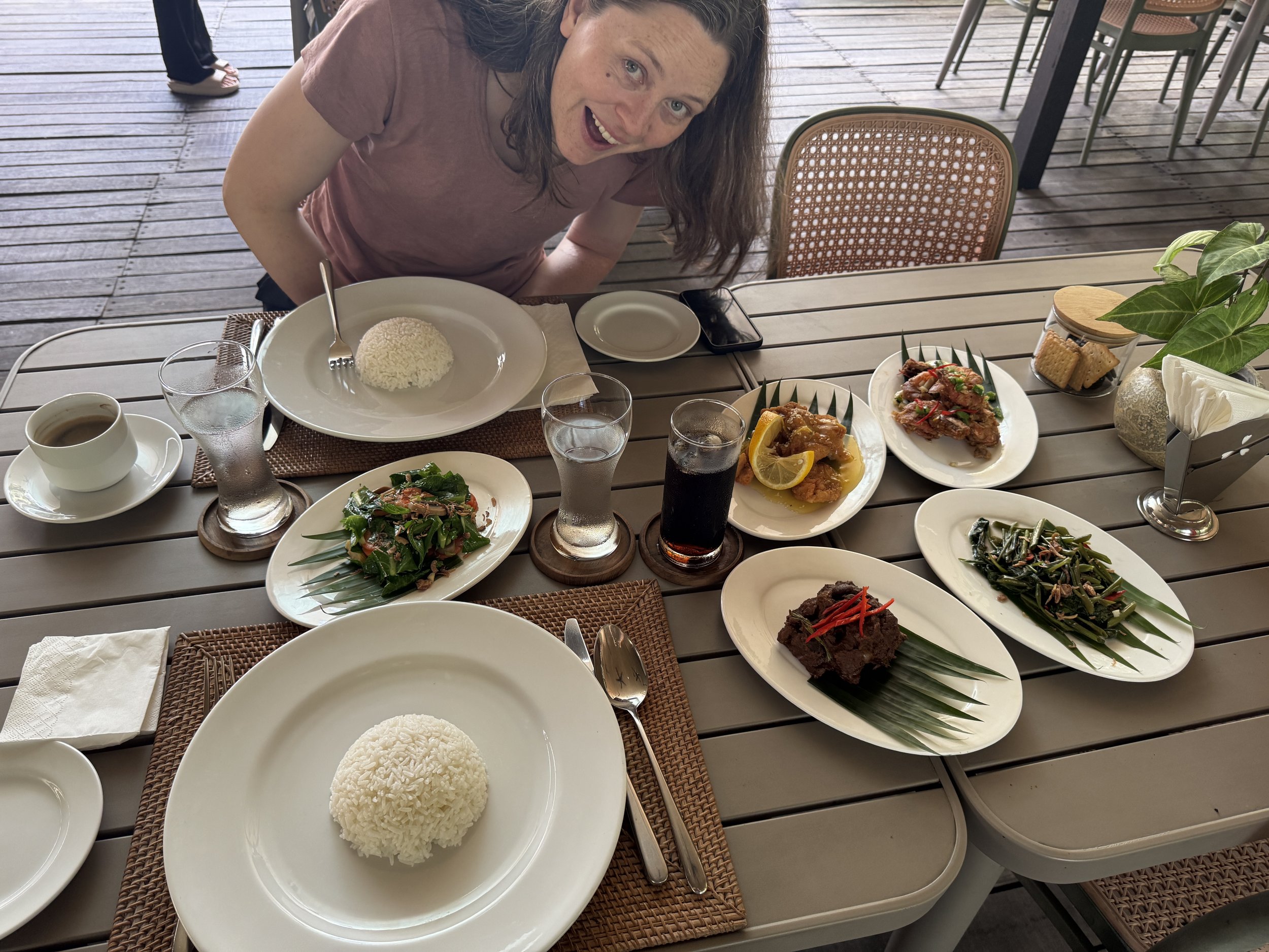 Nicole leaning over several plates of food and smiling excitedly.