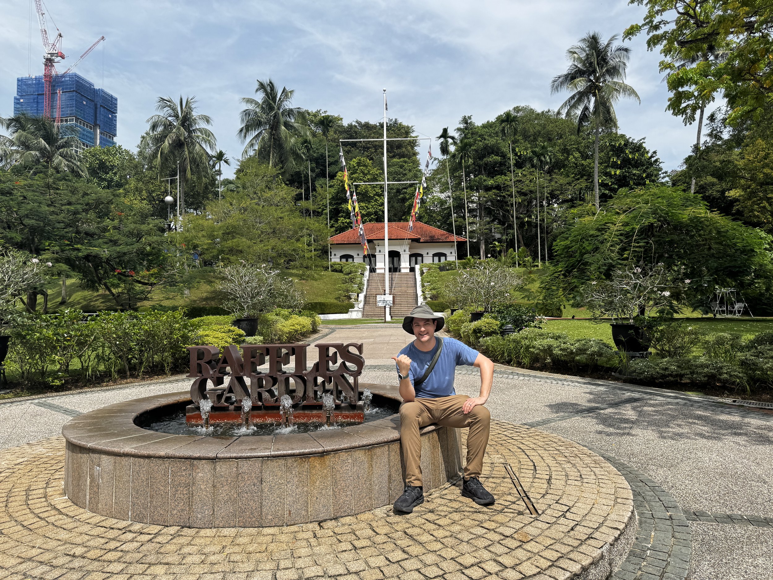 Jason next to a sign that says Raffles Garden.