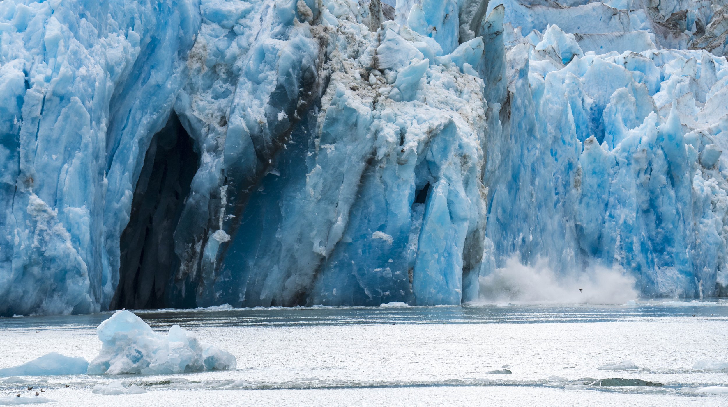 A bright blue glacier calving.