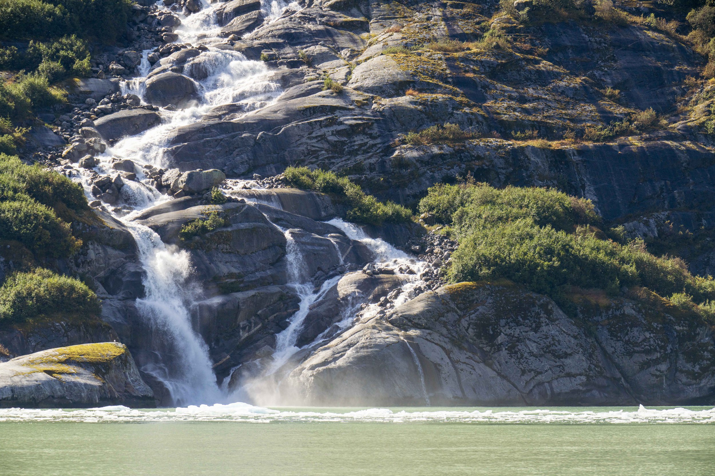 A sunbeam on a waterfall flowing into the ocean.