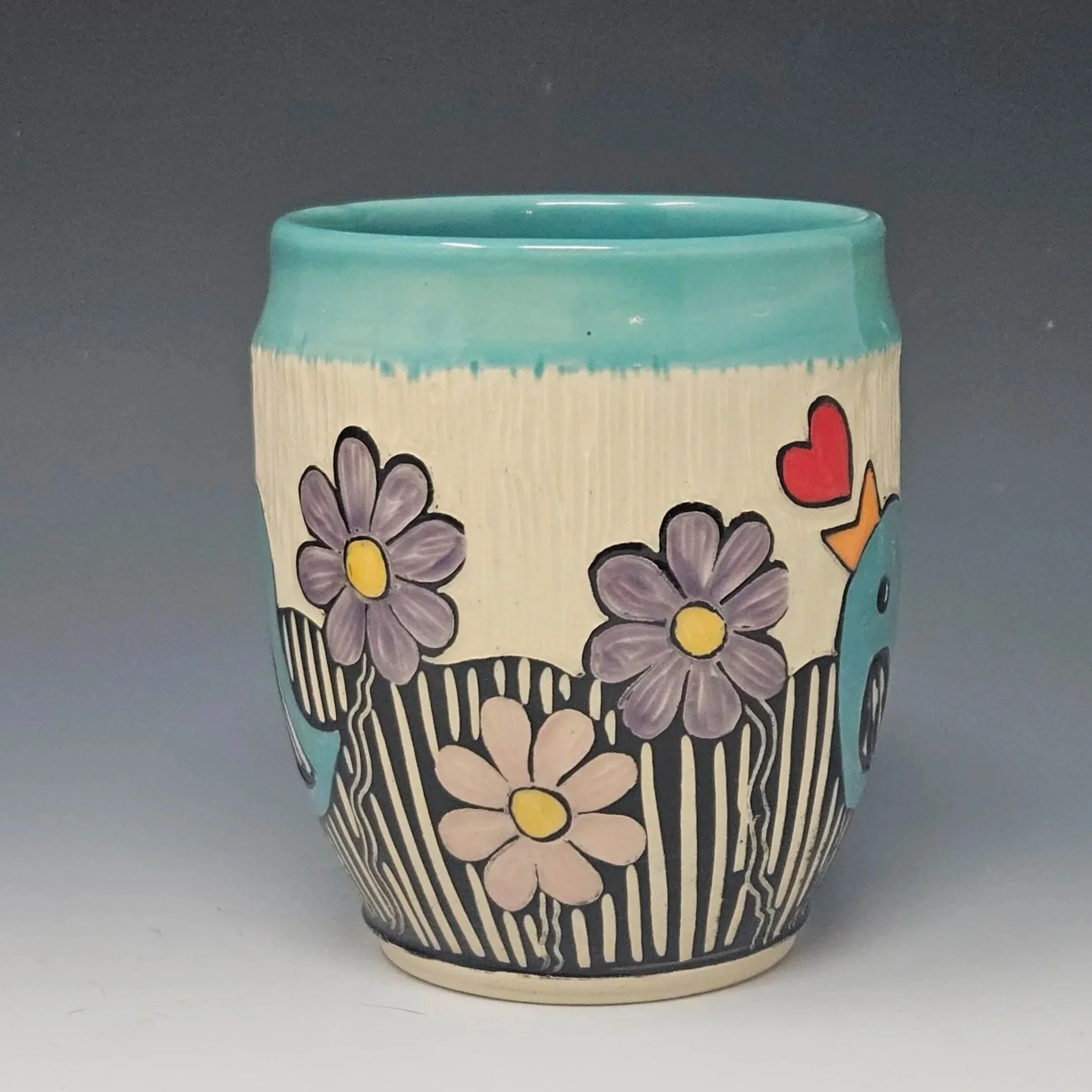 This handmade mug features a little bird and flowers design. This wheel-thrown ceramic art mug has a sgraffito design hand carved on the surface.