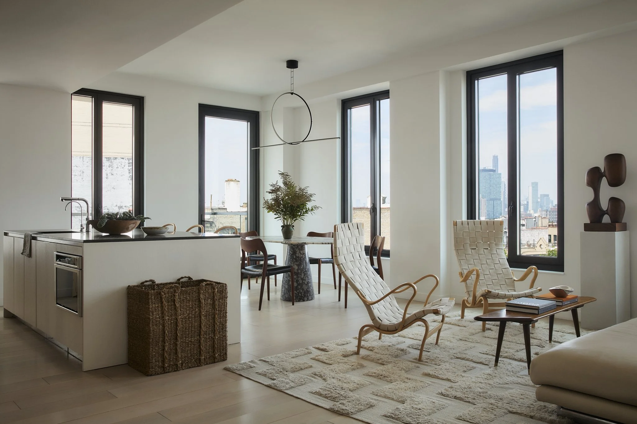 Bright living room with large windows, modern furniture, and decorative sculptures.