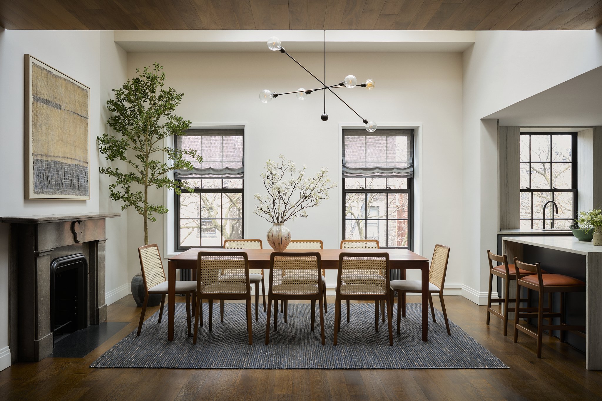 Brooklyn Heights dining room with interiors by Hallie Rose Design, featuring a wood dining table, cane-back chairs, sculptural lighting, and layered natural textures.