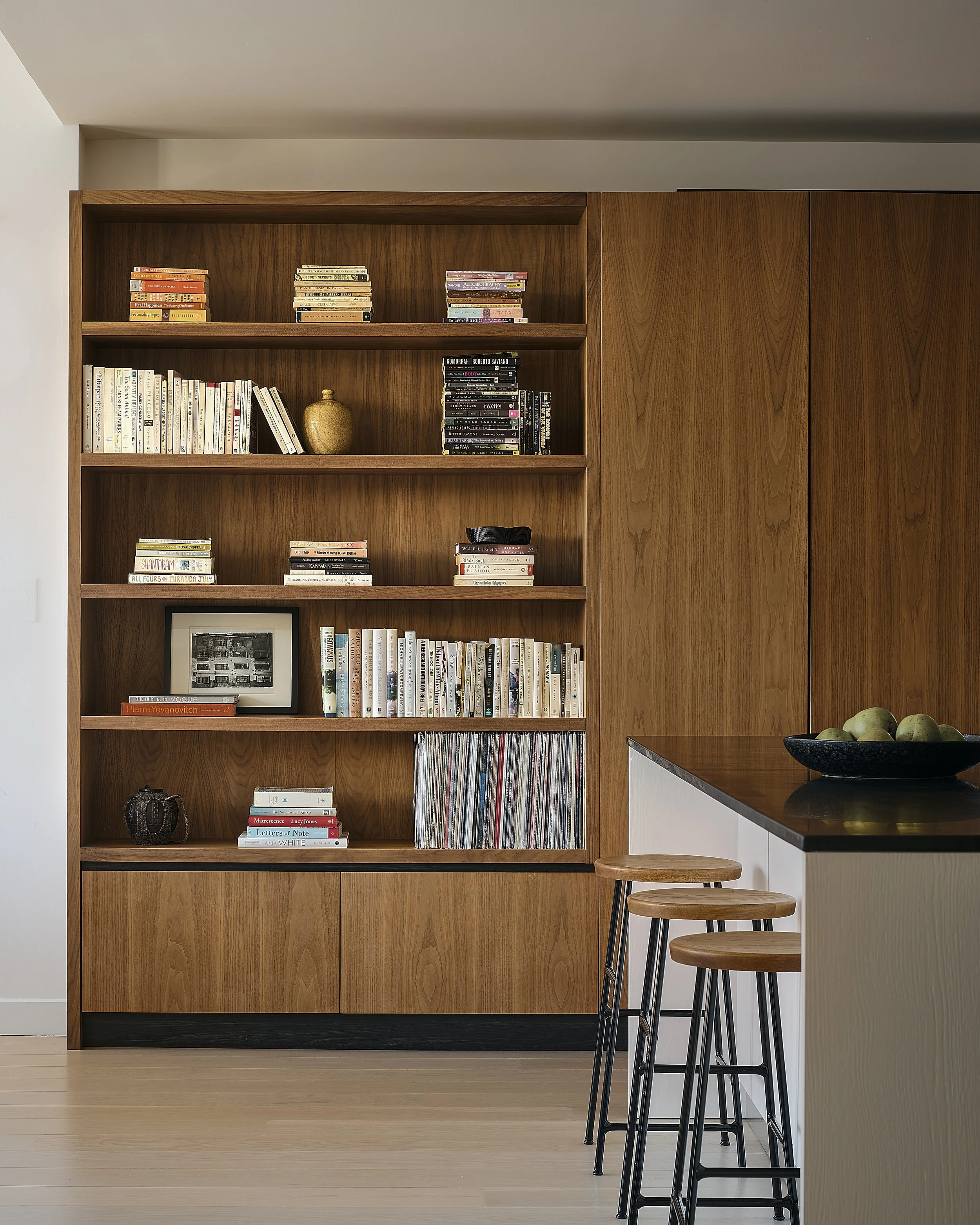 Prospect Heights apartment interior by Hallie Rose Design featuring custom walnut millwork, built-in bookshelves, concealed cabinetry, integrated vinyl-record storage, and curated objects.