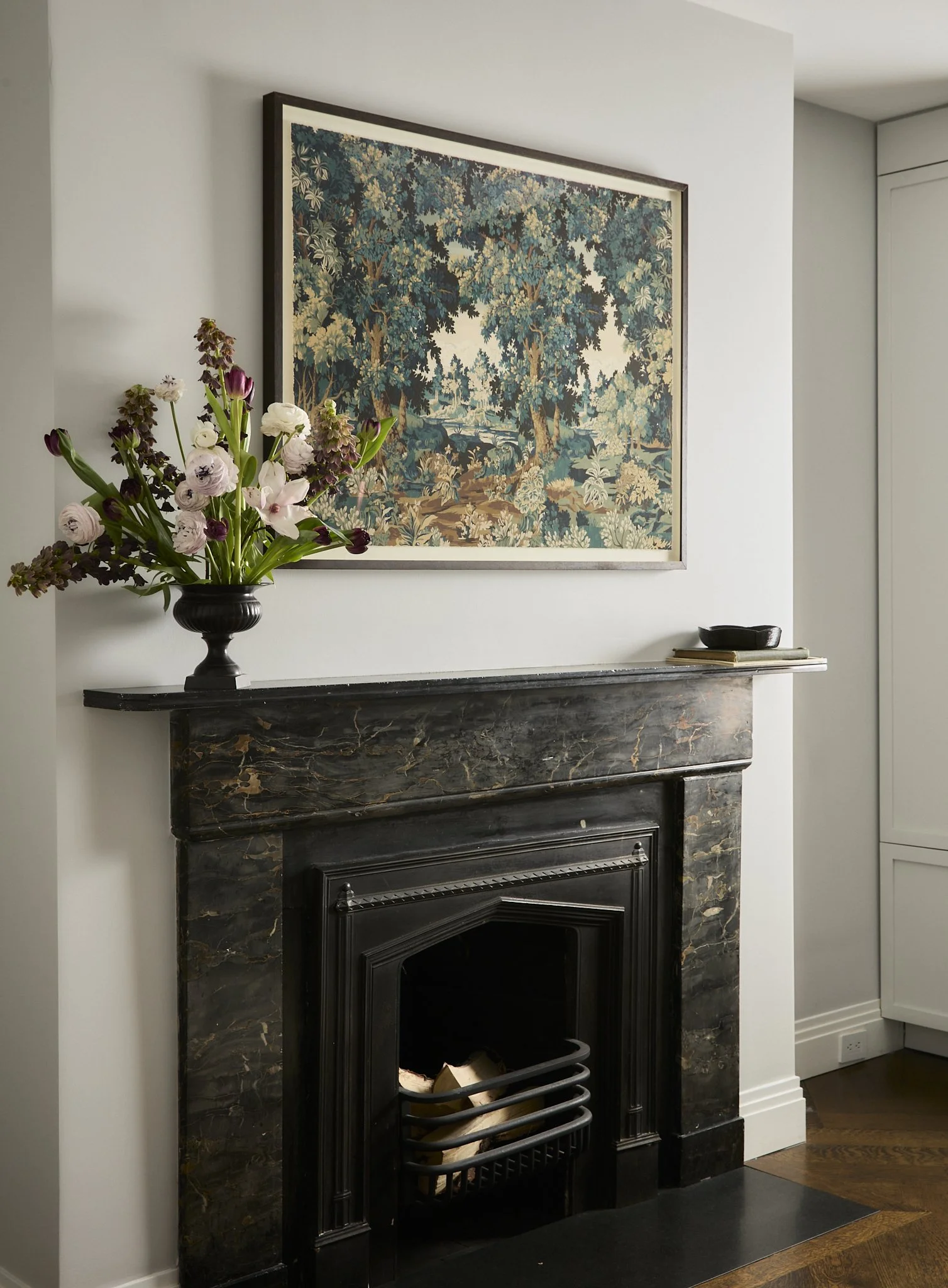 Brooklyn Heights townhouse interior by Hallie Rose Design featuring a black marble fireplace, framed botanical artwork, and sculptural floral arrangement.