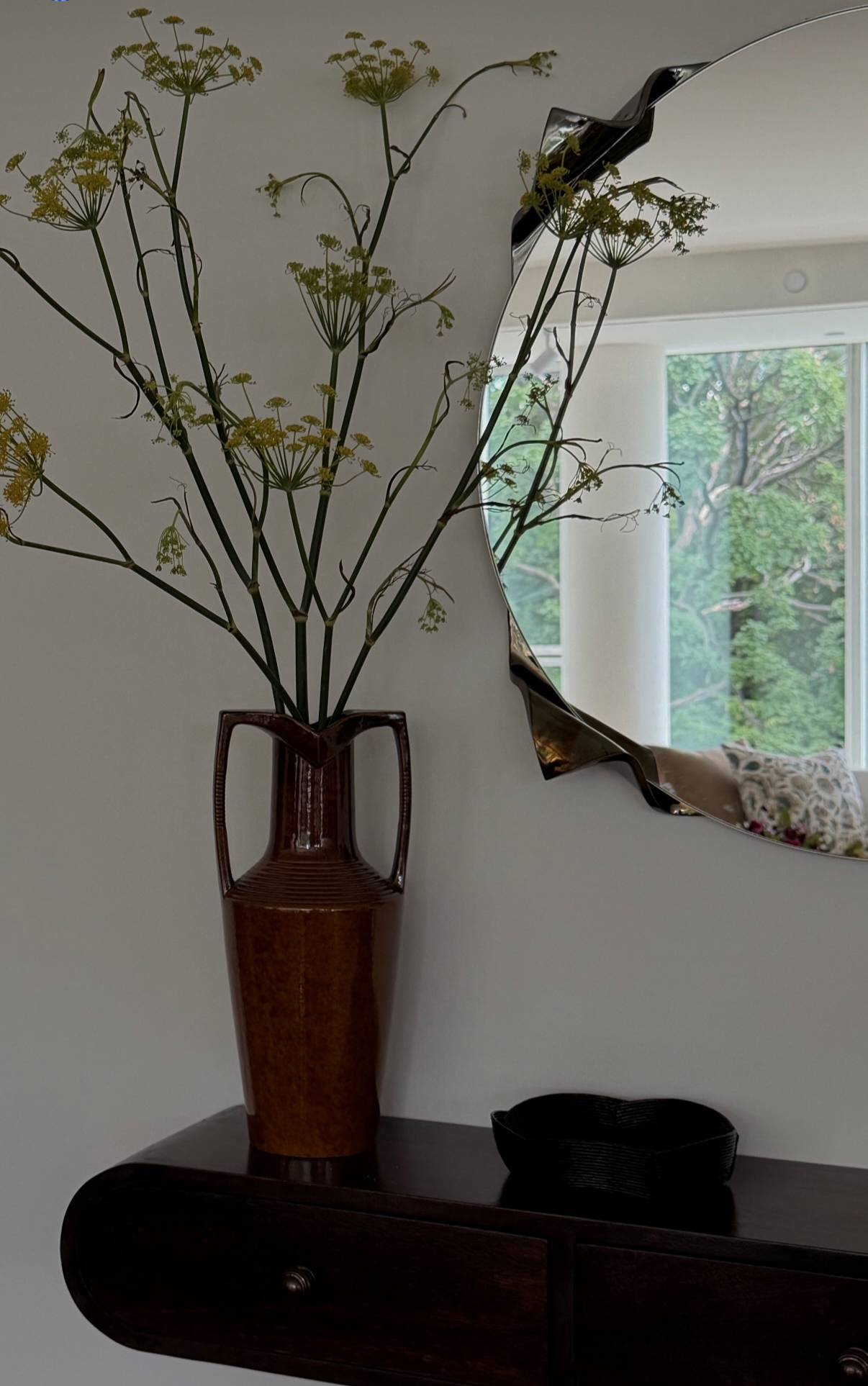 Vintage brown ceramic vase with sculptural branches beside an organic-shaped mirror, styled by Hallie Rose Design.