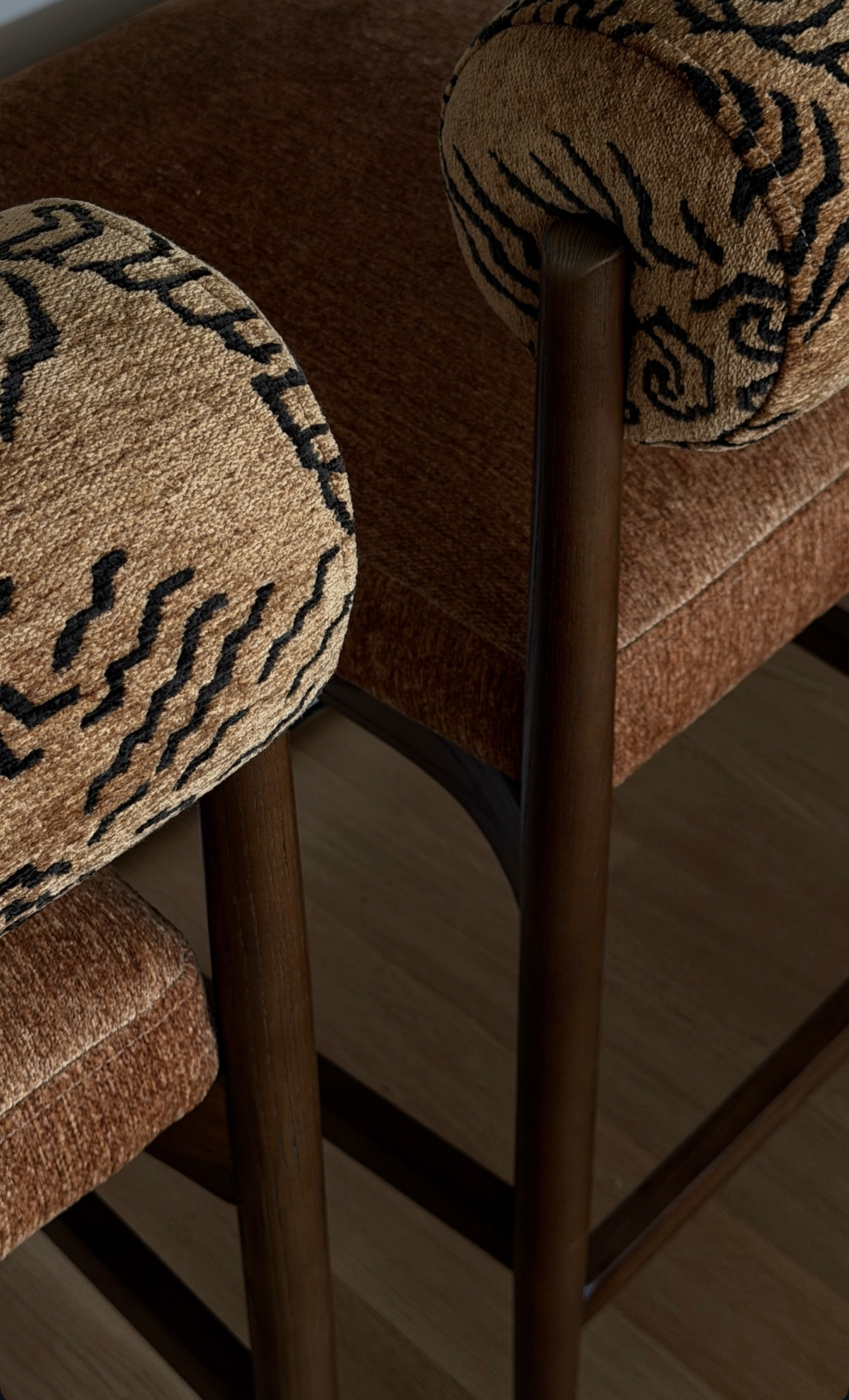 Close-up of custom upholstered seating by Hallie Rose Design, featuring patterned textile, warm brown chenille upholstery, and sculptural dark wood frames