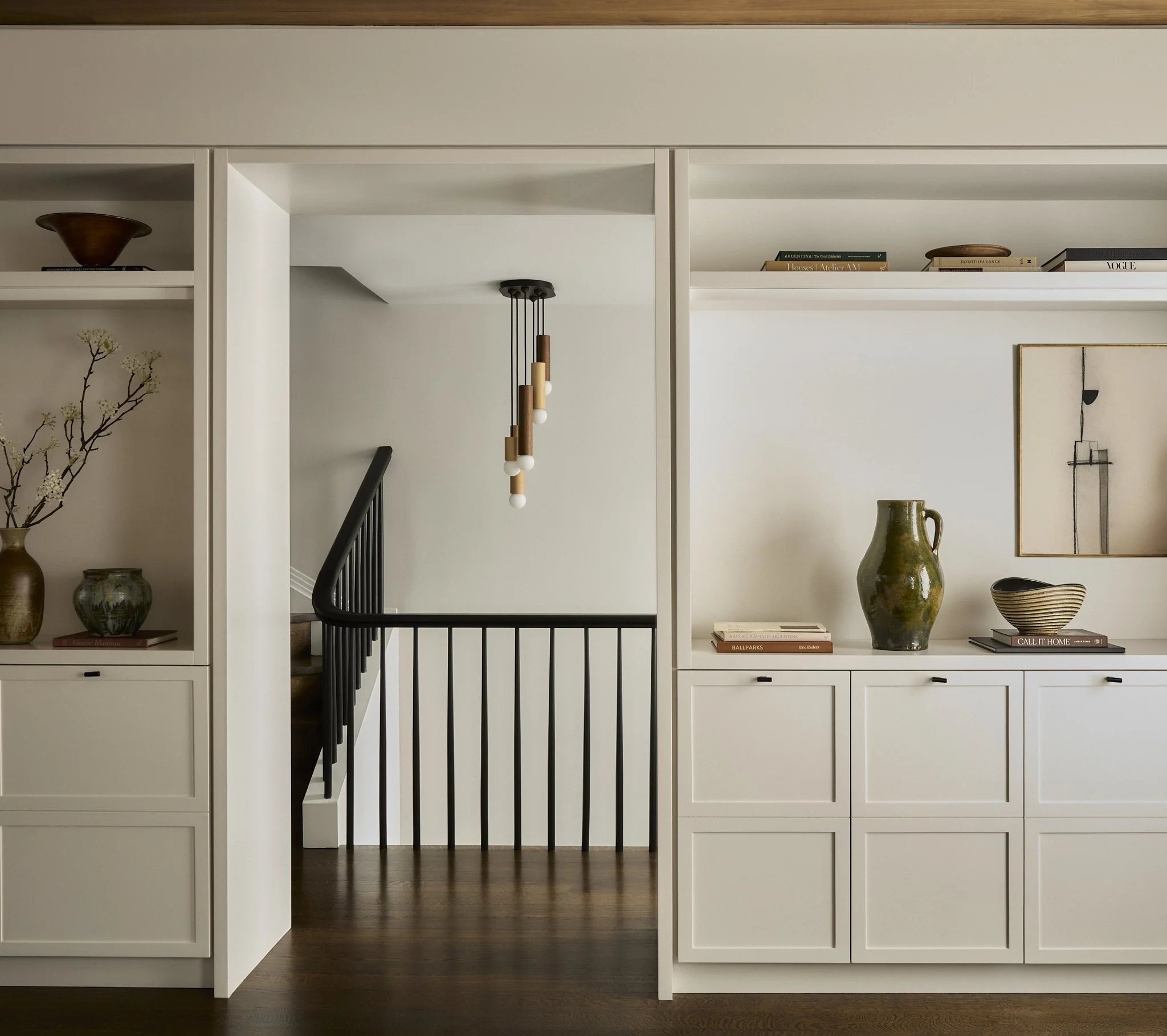 Brooklyn Heights townhouse stairway with interiors by Hallie Rose Design, featuring sculptural pendant lighting, built-in shelving, and collected ceramic vessels.