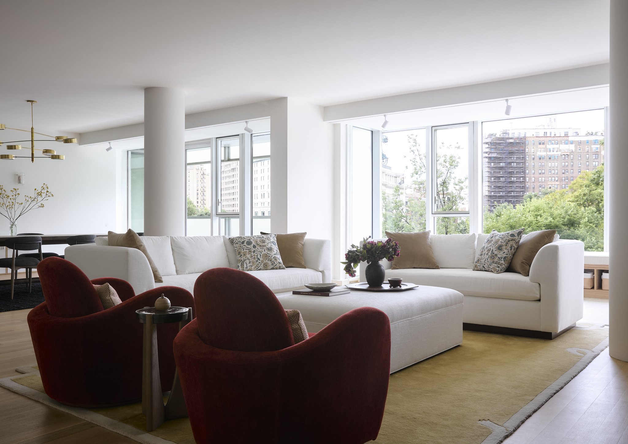 Living room interior design with white linen sofas and red velvet swivel chairs overlooking Central Park, New York City