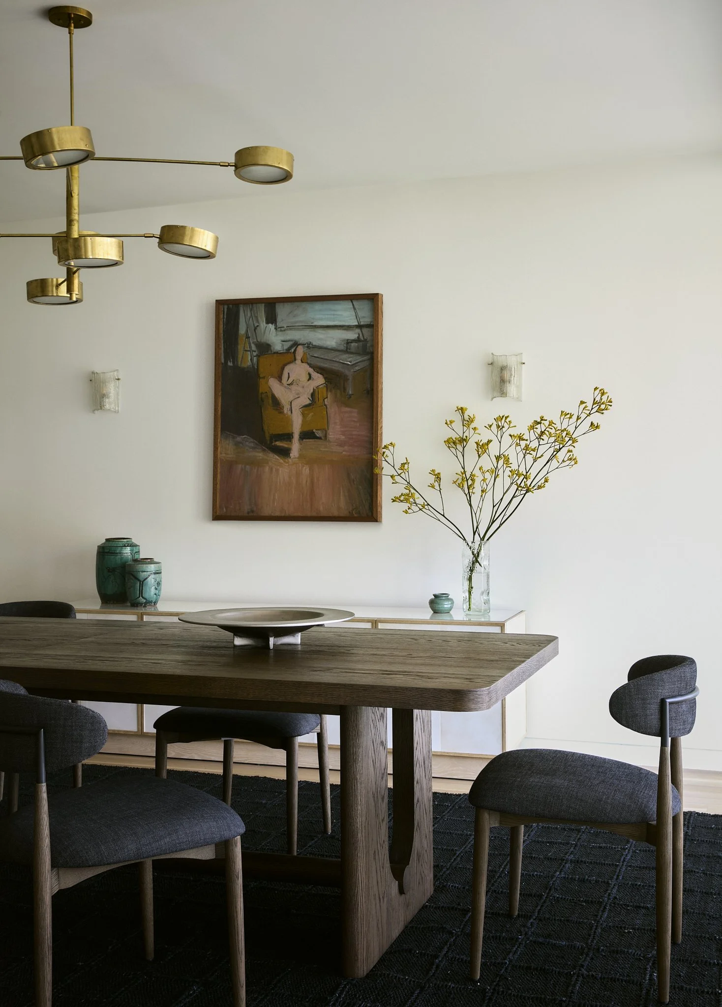 Dining room with a dark oak trestle table, sculptural brass chandelier, and figurative painting in a New York City home