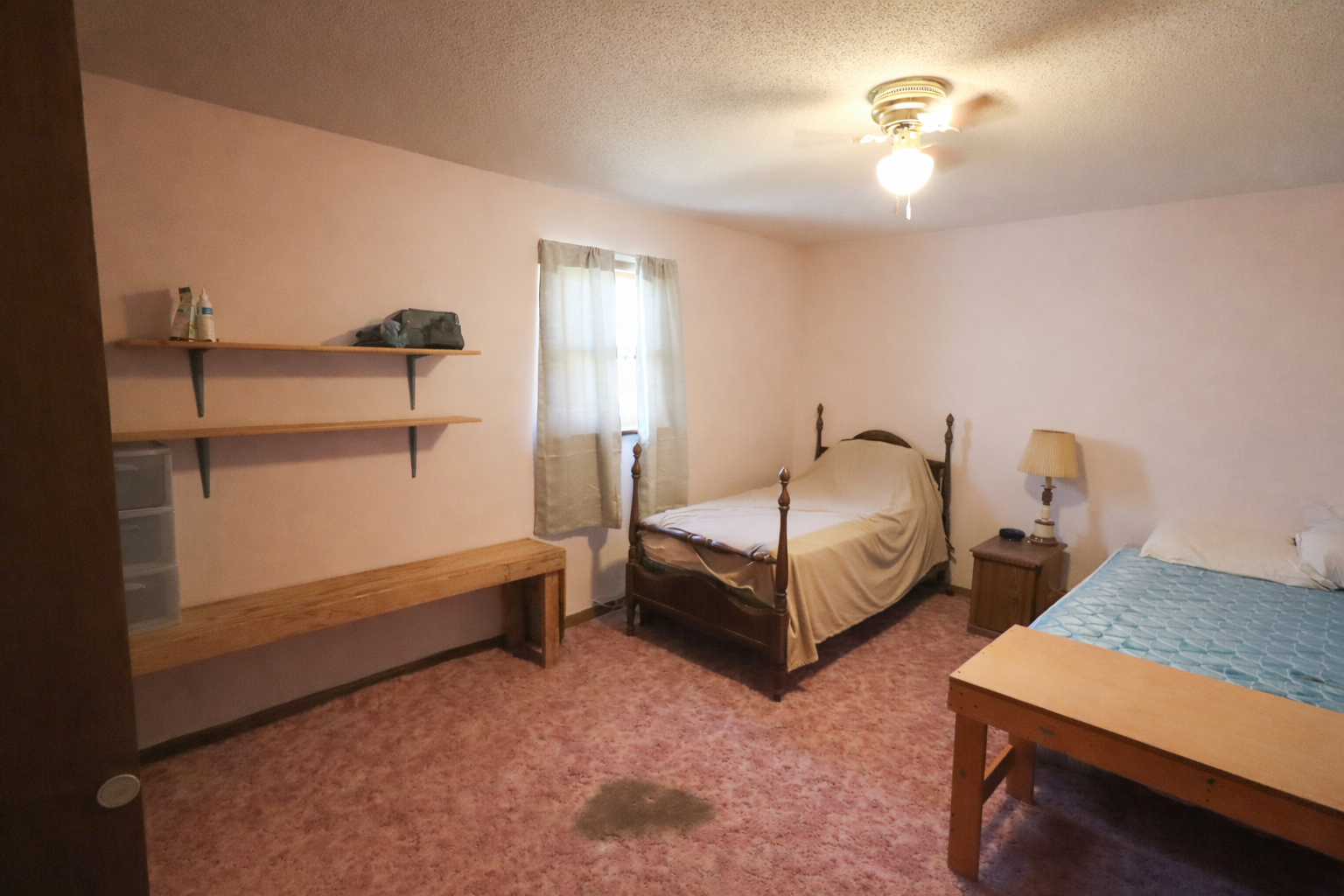 Simple pink bedroom with wooden furniture.png